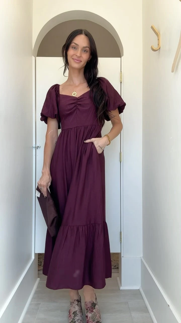 Plum puff-sleeve midi dress styled with a gold pendant, tapestry platform clogs, and dark brown clutch.