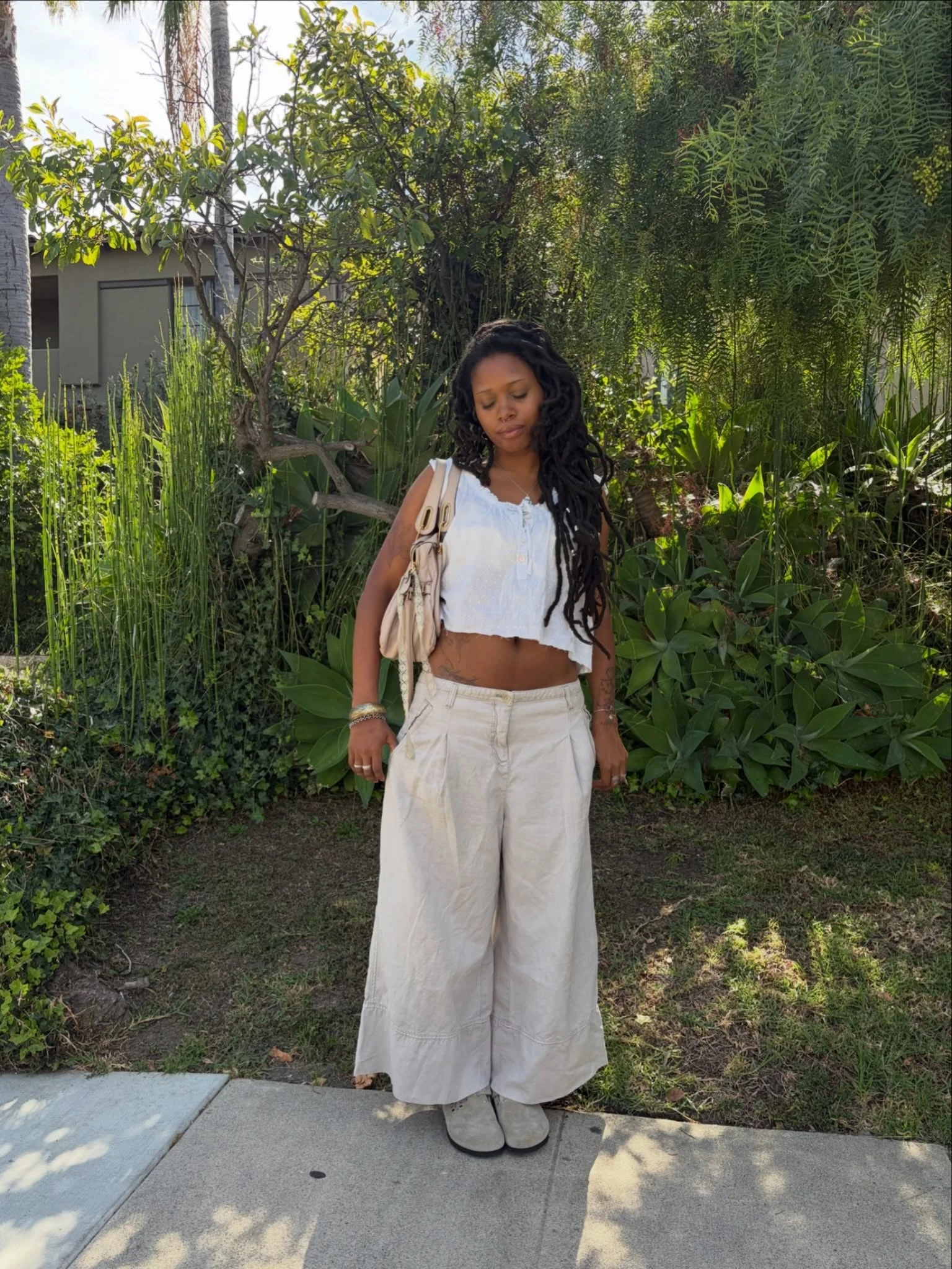 white sleeveless cropped blouse, high-waisted wide-leg beige trousers, light gray suede clogs