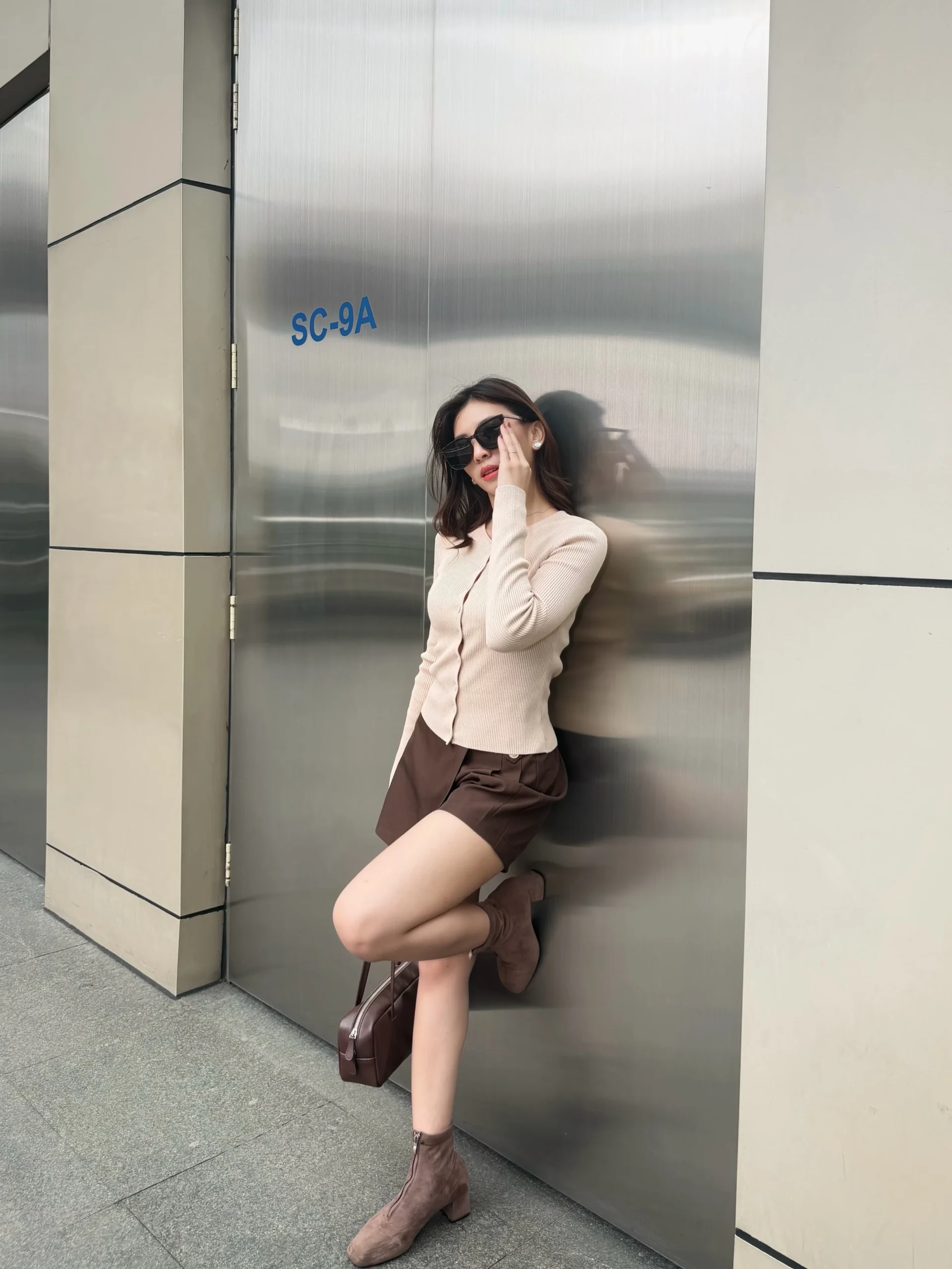 light beige ribbed cardigan, brown tailored shorts, taupe ankle boots, brown handbag