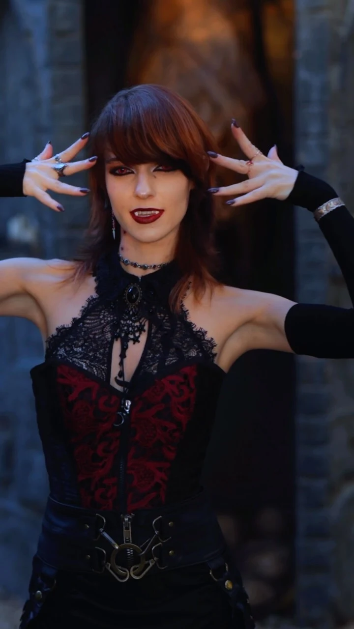 Black and red gothic outfit featuring a lace corset bodice, wide belt, and long dramatic gloves.
