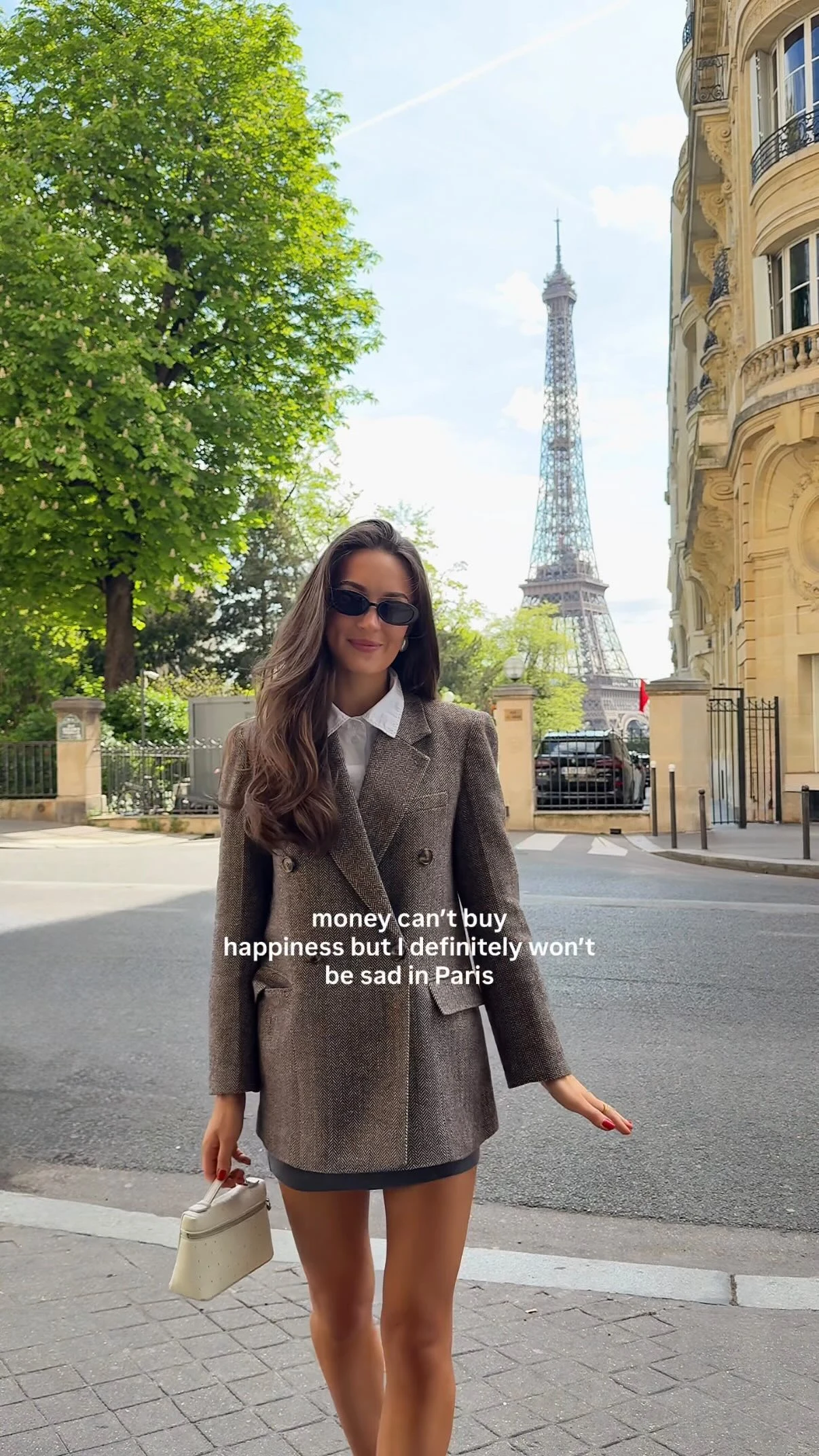 Oversized brown double-breasted blazer over white shirt and dark skirt with cream handbag.