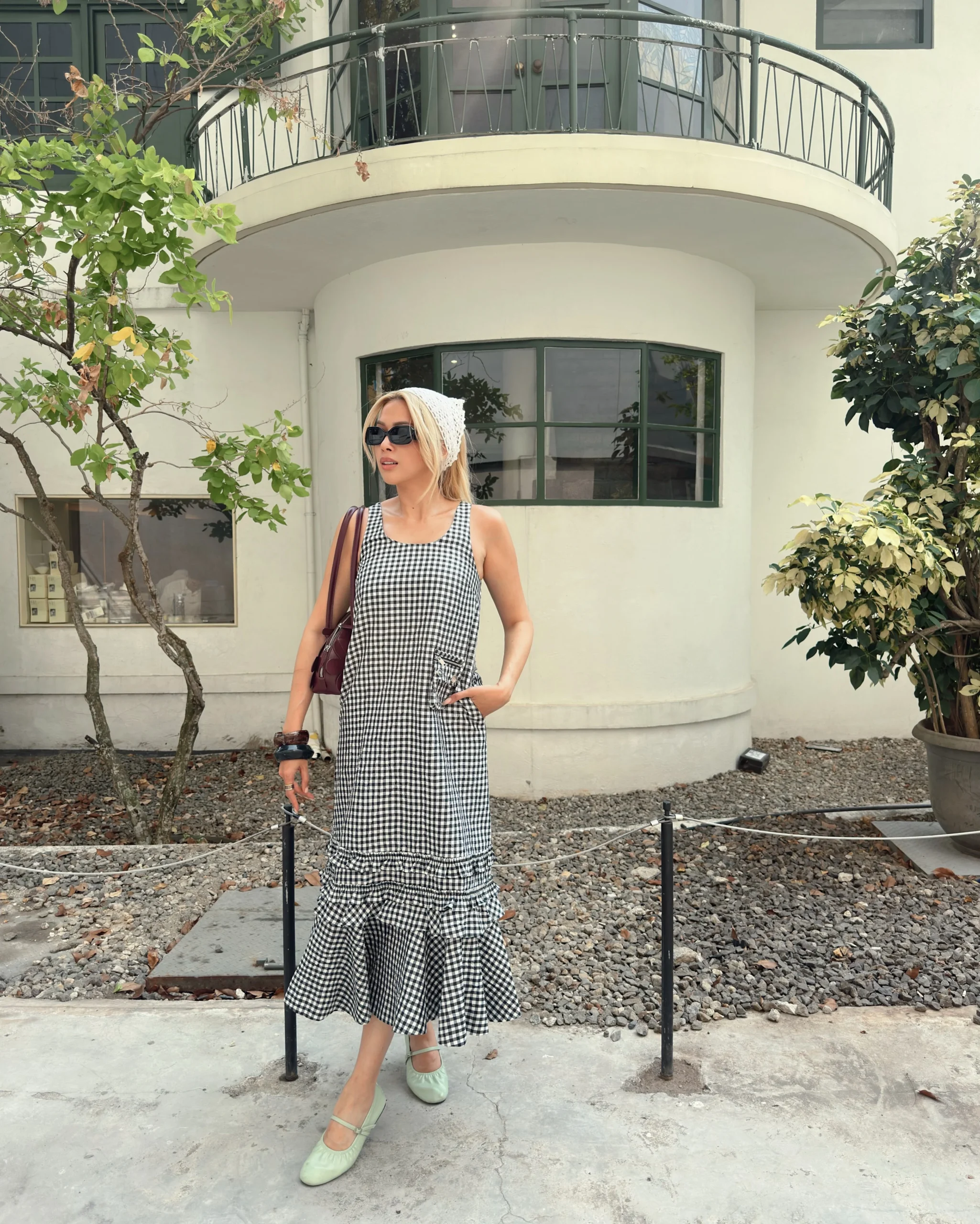 Black and white gingham midi dress styled with mint Mary Jane shoes, crochet headscarf, and burgundy floral bag.