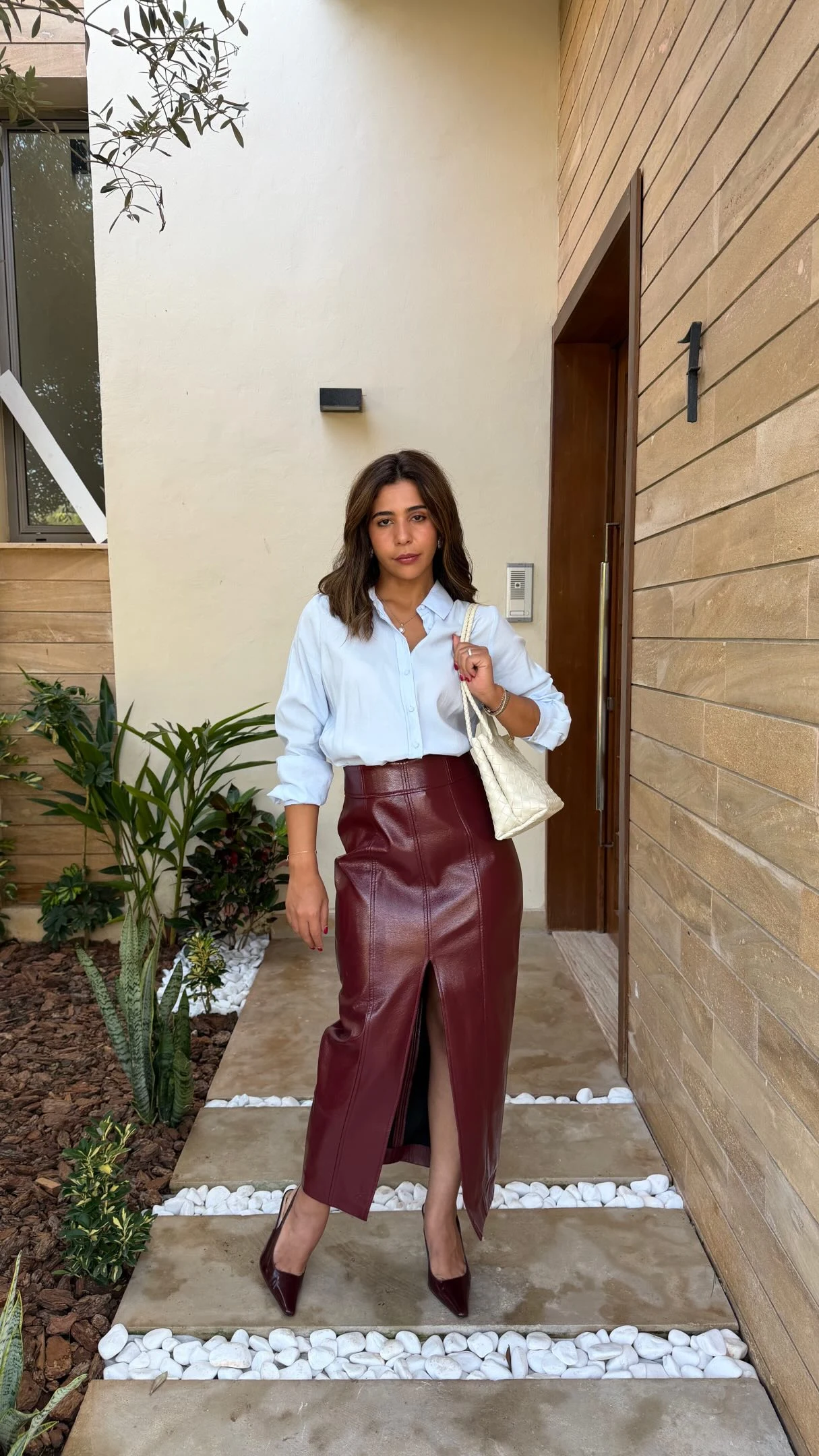 light-blue button-down shirt, high-waisted burgundy faux-leather pencil skirt with front slit, black tights, black heels
