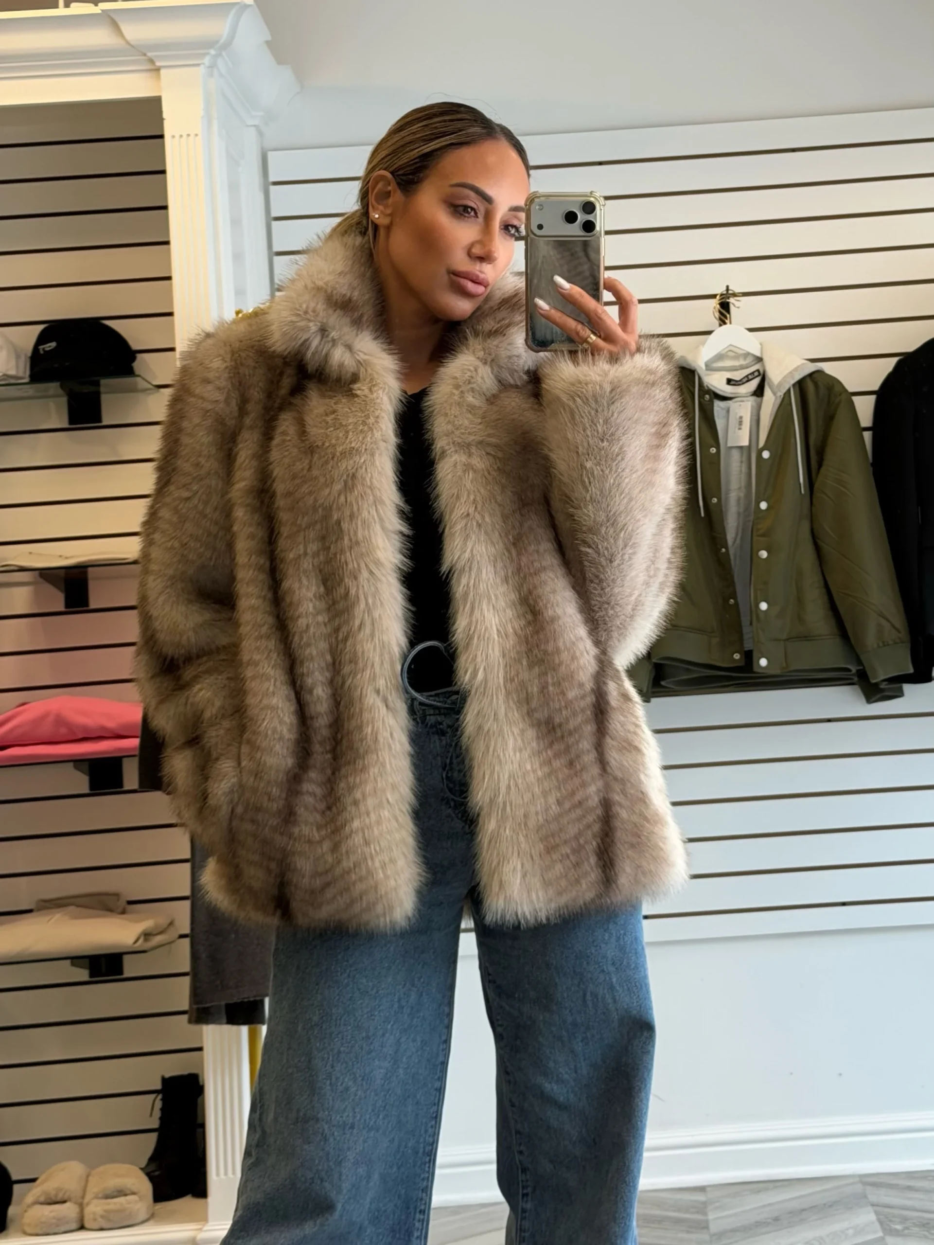 Light brown faux-fur coat styled with a black t-shirt and blue wide-leg jeans.