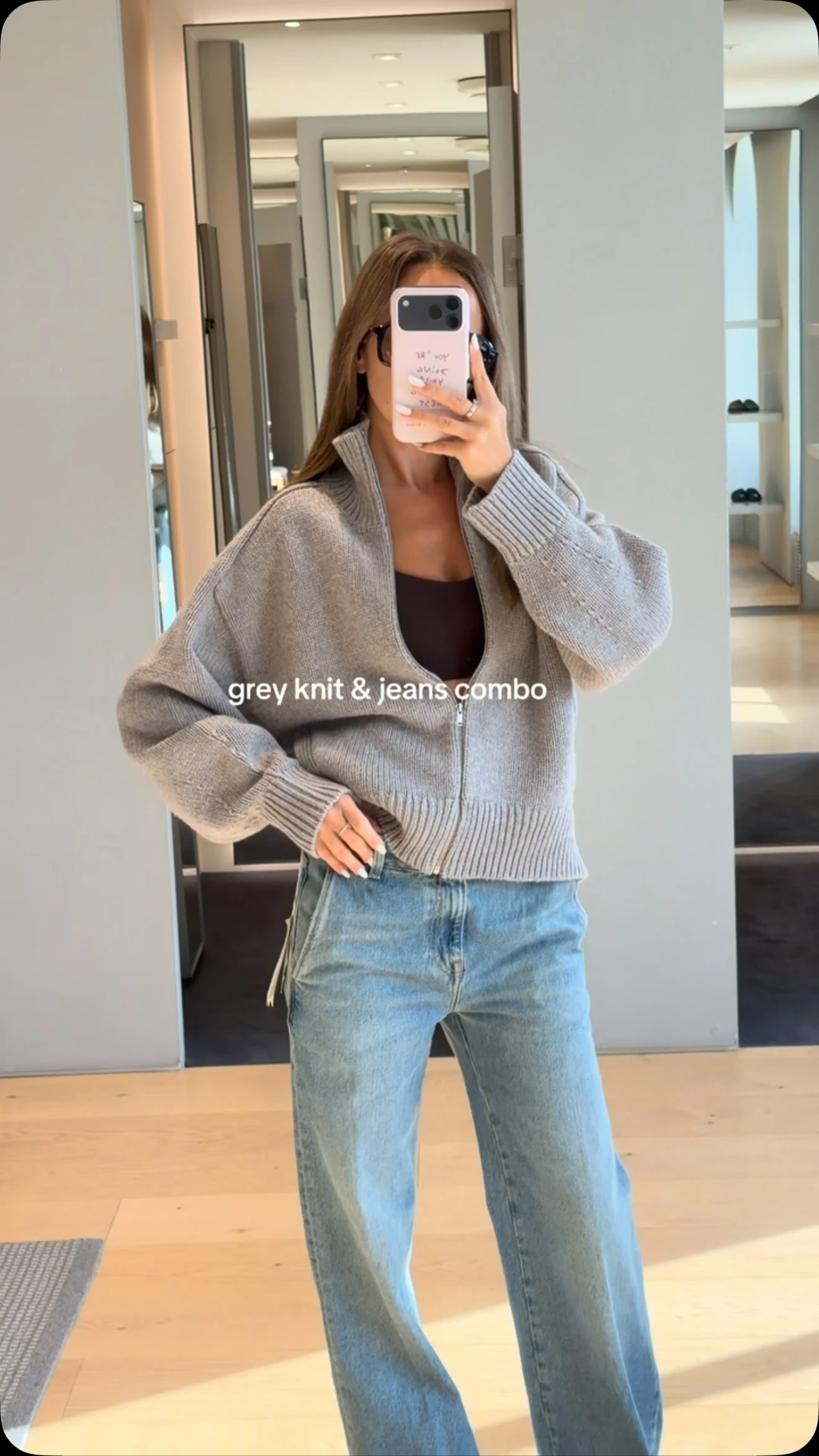Oversized light grey zip-up cardigan over a white top with light-wash wide-leg jeans.