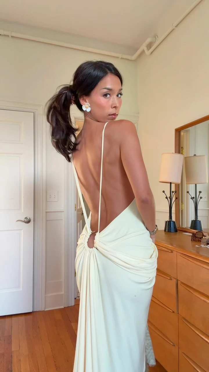 Pale green backless floor-length gown with draped detail and large flower-shaped earrings.