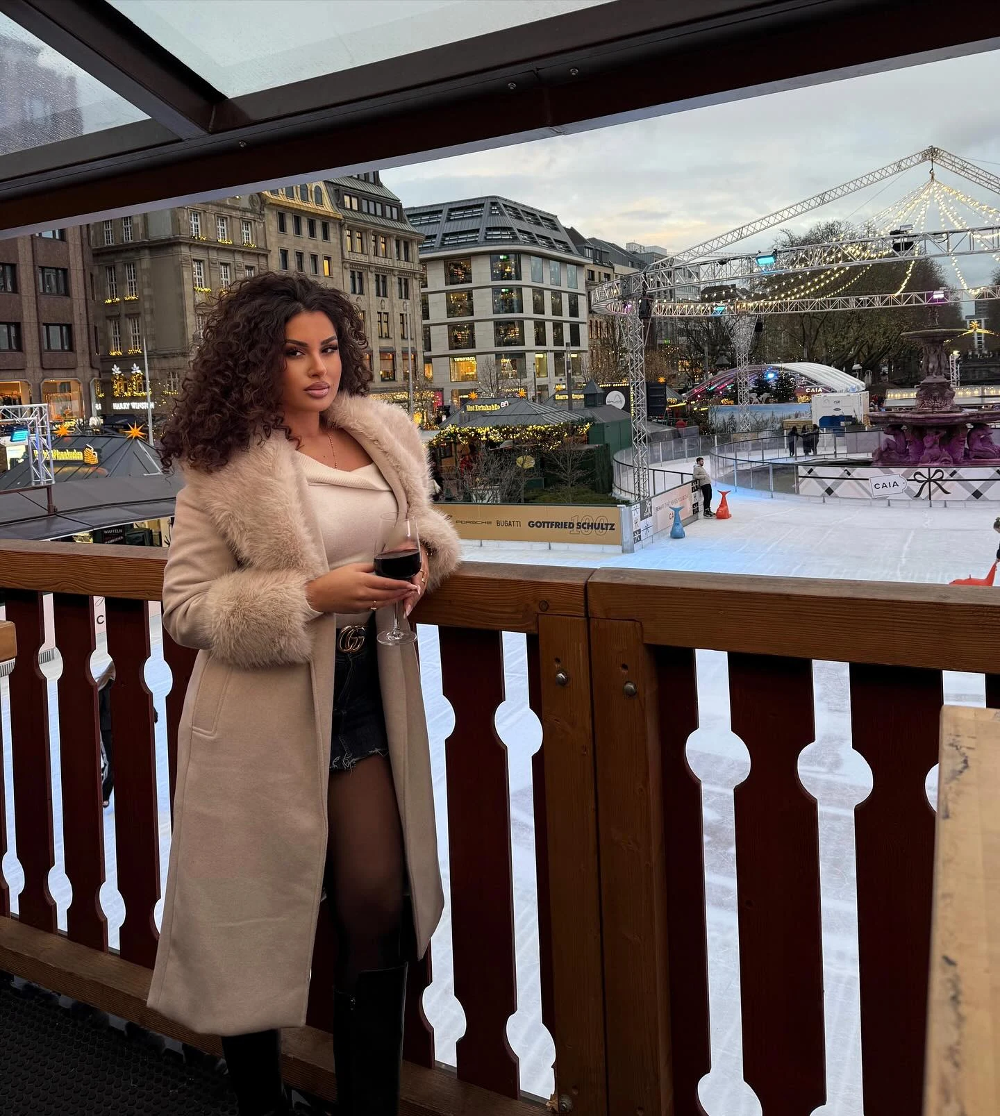 Person in a white faux-fur trimmed coat, light knit sweater, dark leggings, and winter boots.