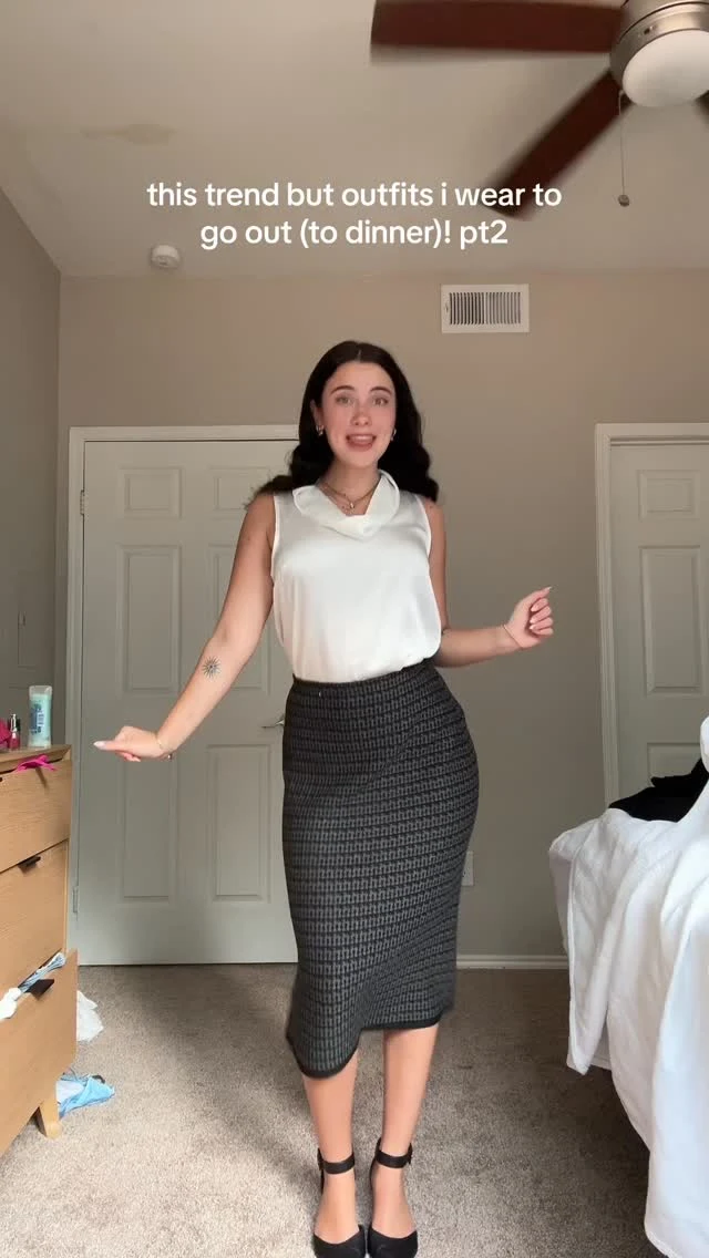 White sleeveless collared blouse tucked into a fitted dark gray patterned midi skirt with black ankle-strap shoes.