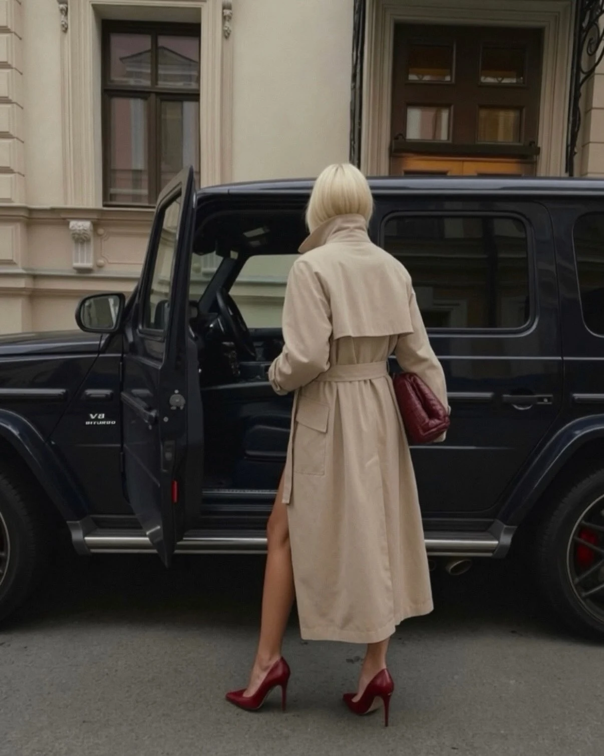 Person from behind wearing a belted beige trench coat with red heels and a red quilted bag.