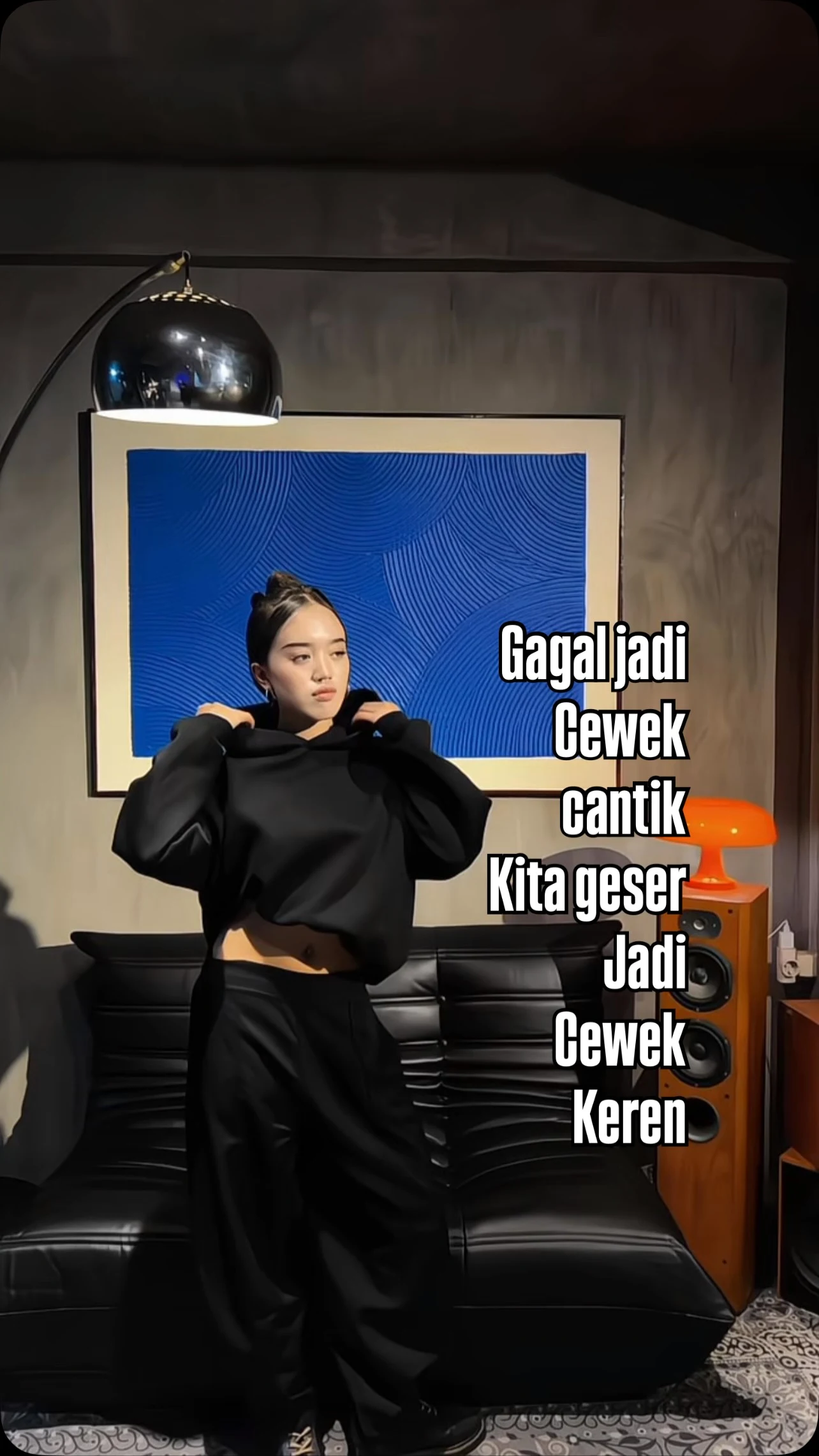 Person in a black cropped oversized hoodie and black wide-leg pants with midriff showing.