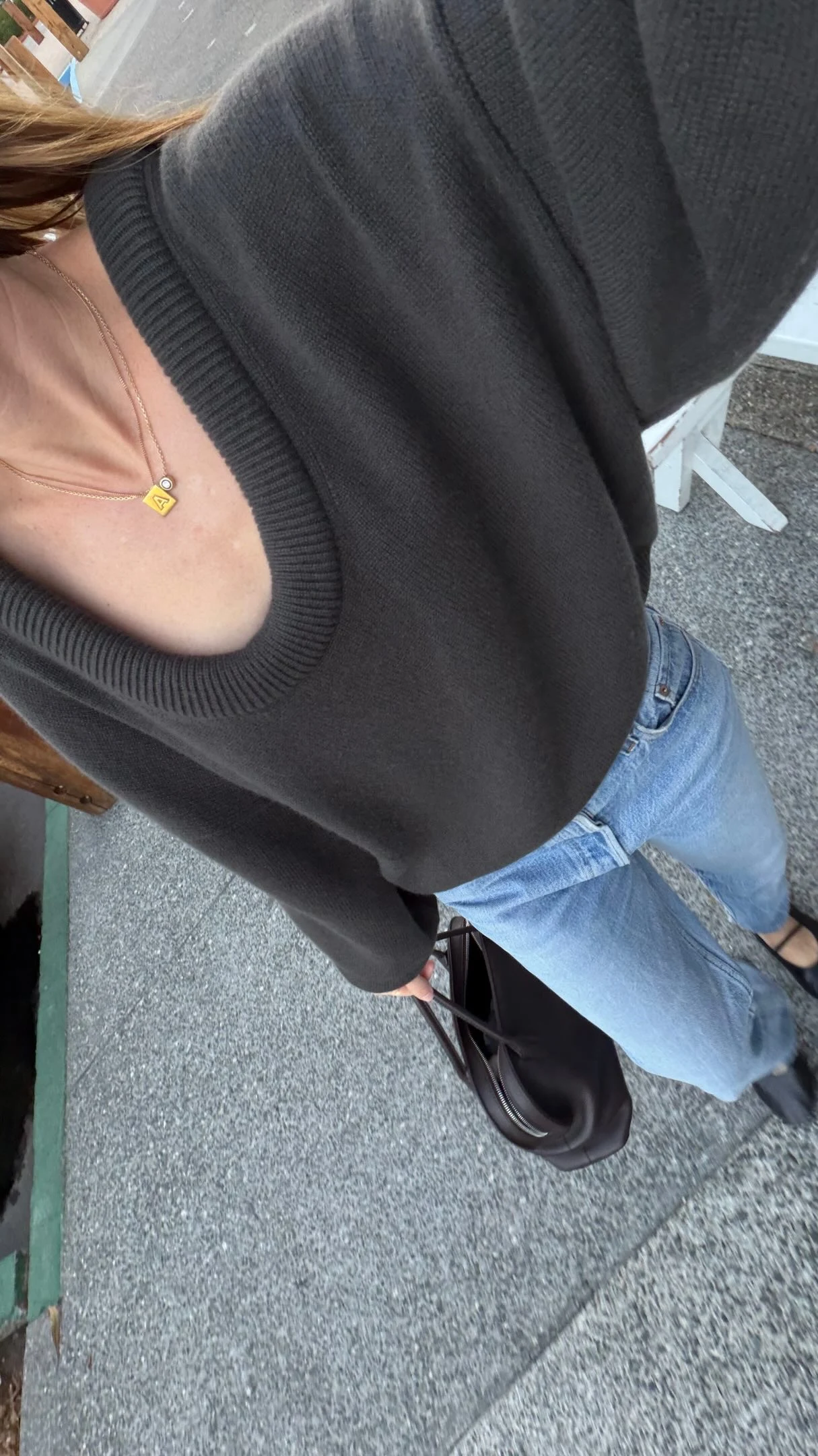 Overhead view of a charcoal oversized V-neck sweater paired with light blue jeans and a gold necklace.