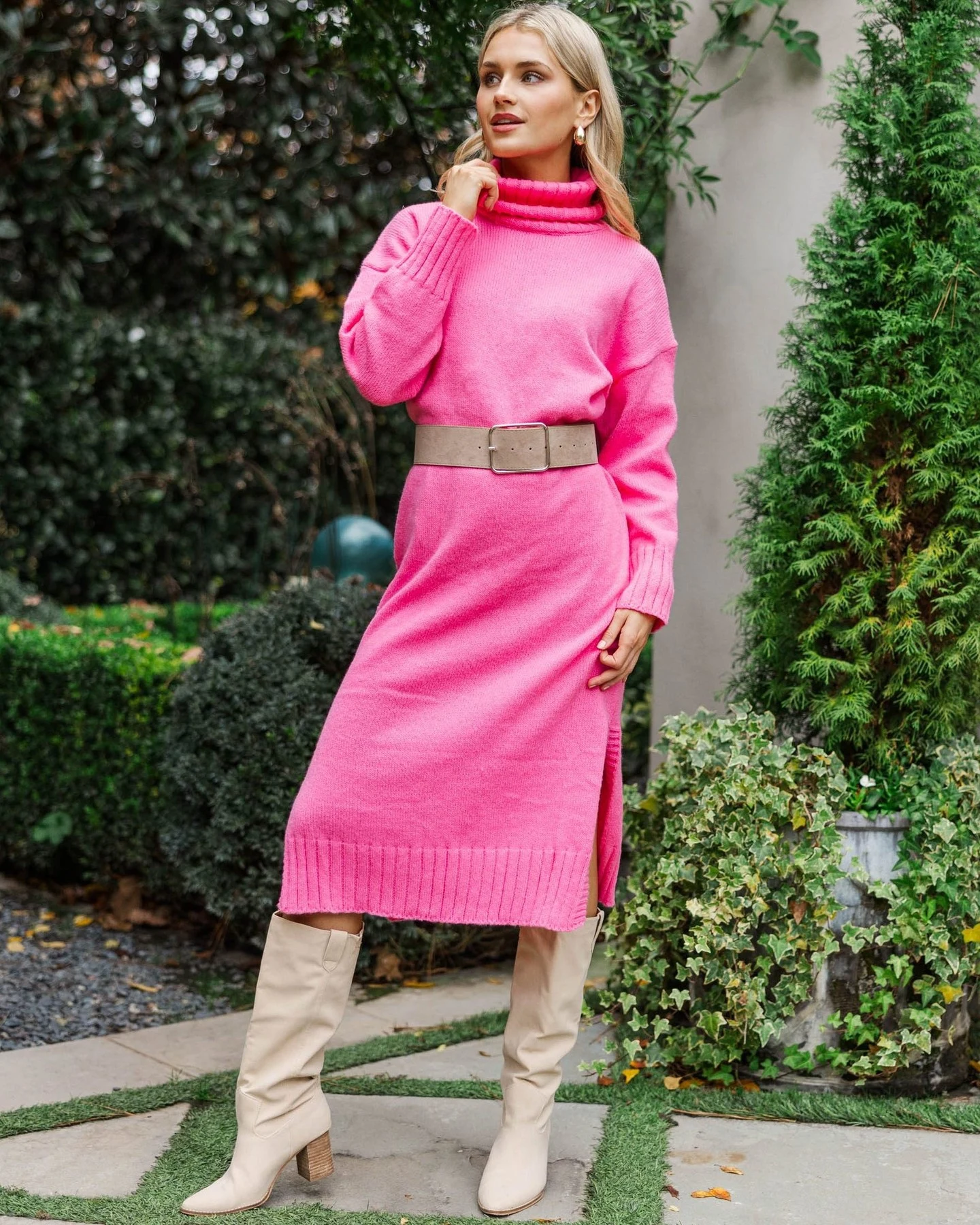 Woman wearing a hot-pink turtleneck sweater dress with black knee-high boots.
