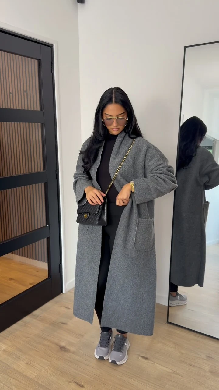 Oversized grey wool coat over all-black outfit with chunky sneakers and quilted crossbody bag.