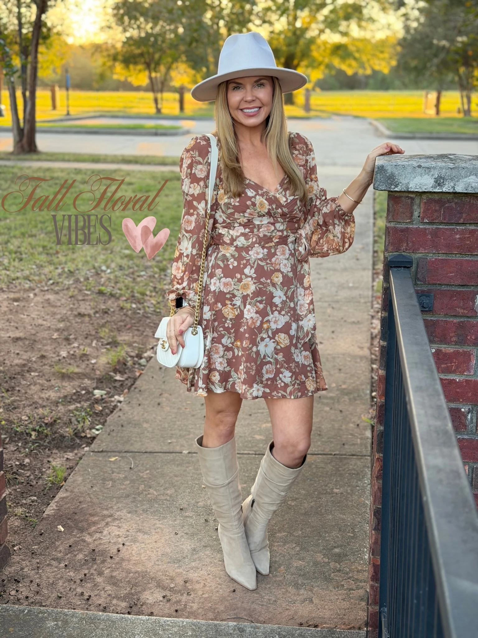 Brown floral mini dress with beige knee-high boots, wide-brimmed hat, and white shoulder bag.