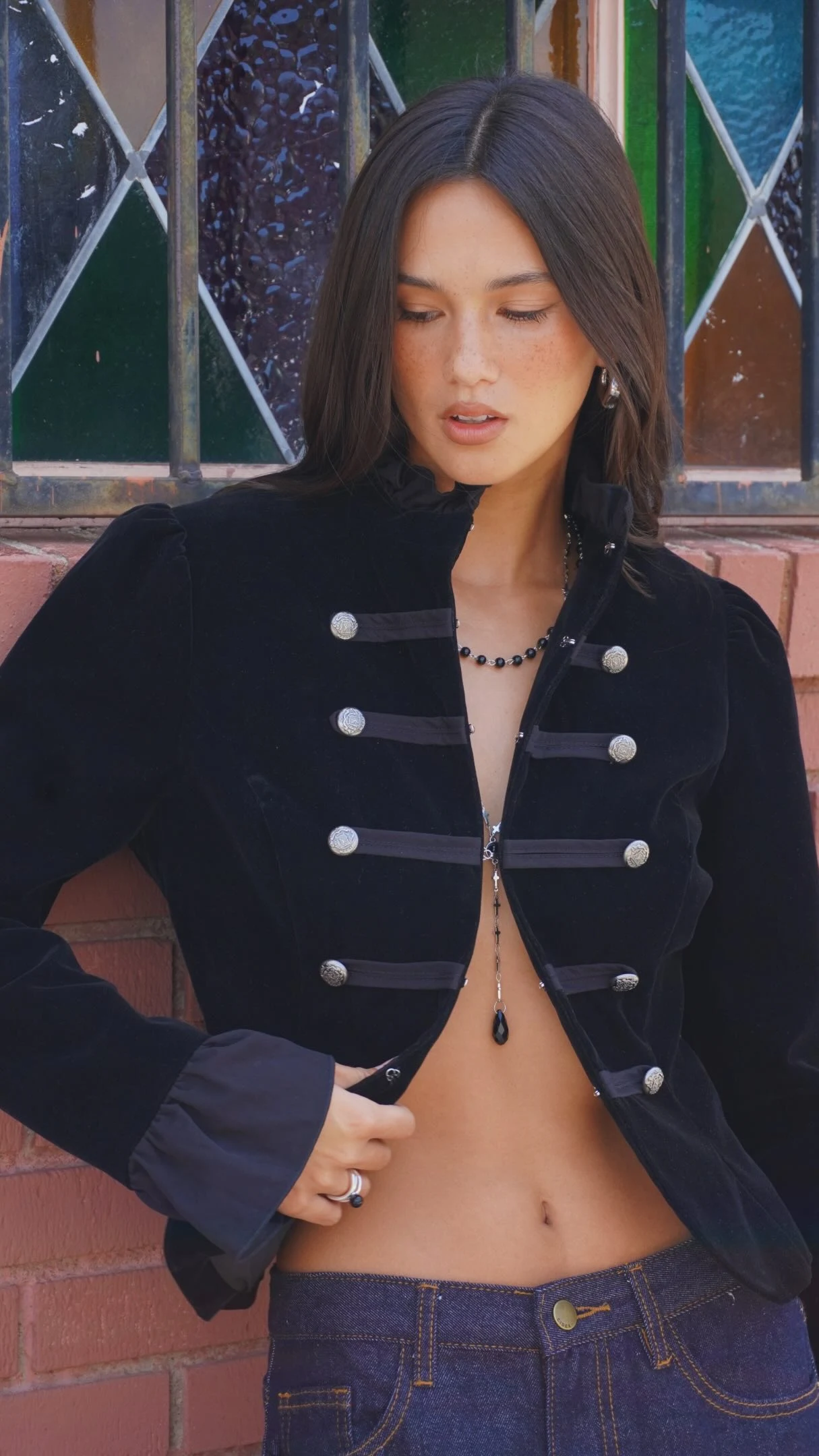 Cream puff-sleeve jacket tied at the waist over black leggings with burgundy pointed heels.