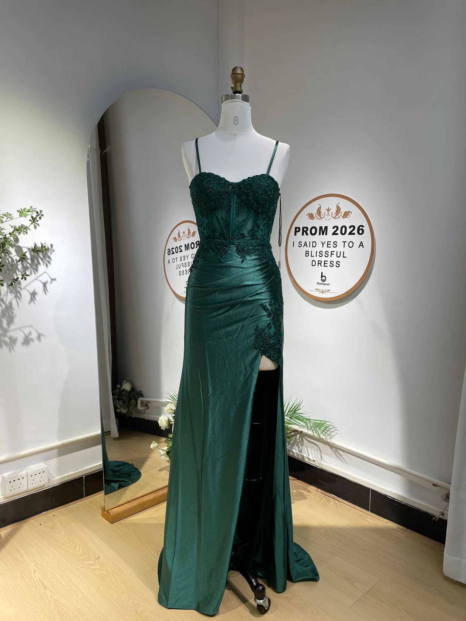 Emerald green satin mermaid gown with floral mesh embroidery, spaghetti straps, sweetheart neckline, and high leg slit.