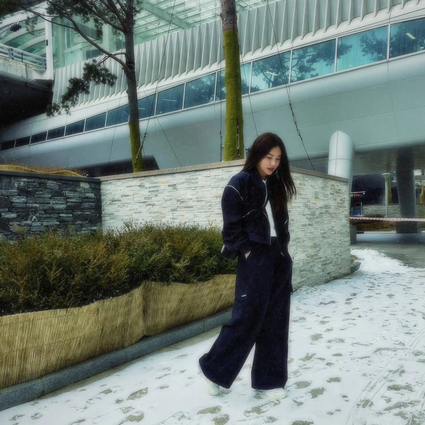 Person in a navy corduroy tracksuit set, white crew neck, and chunky white sneakers.