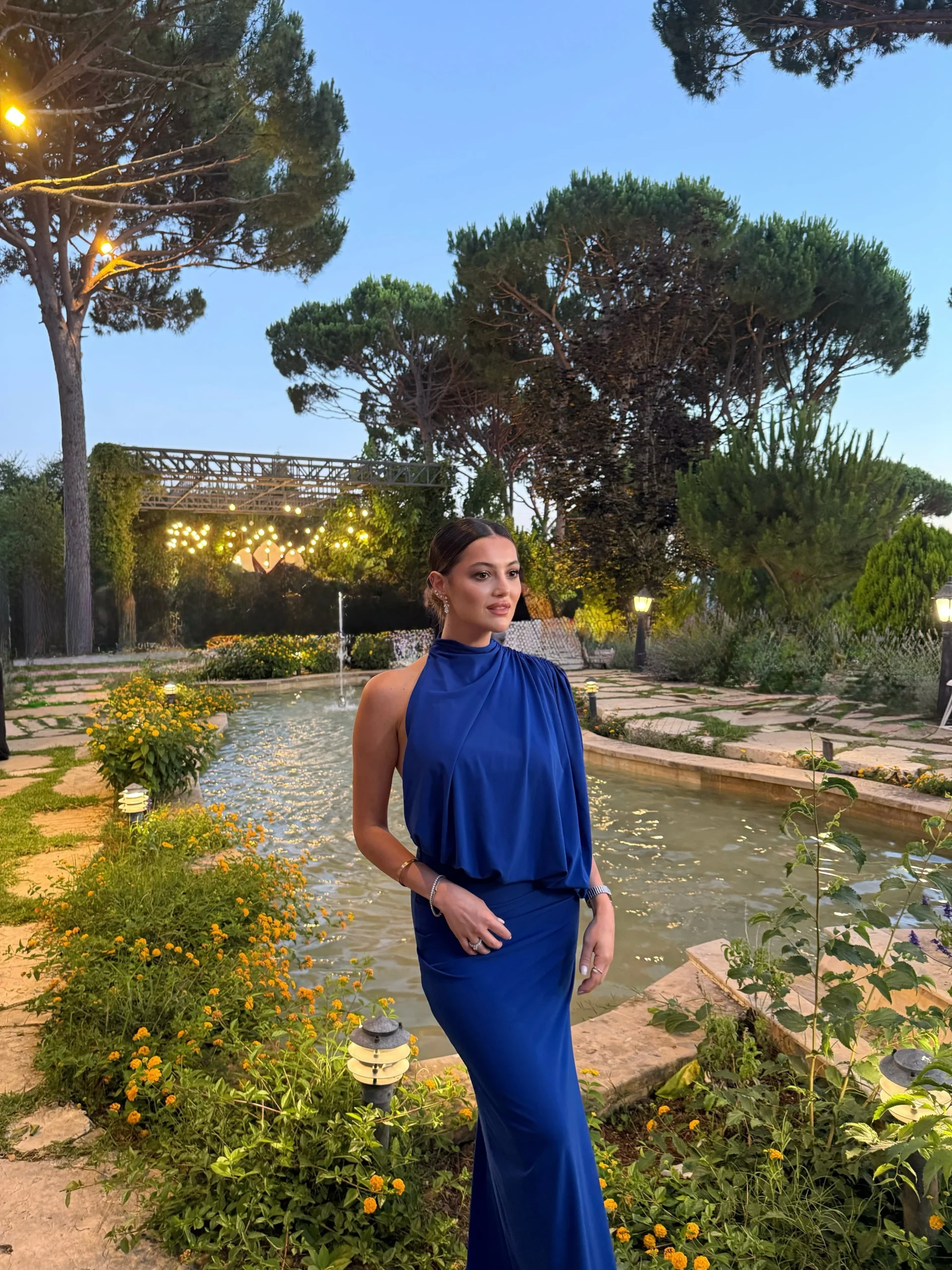 Floor-length royal blue sleeveless halter gown with soft bodice draping and fitted straight skirt.