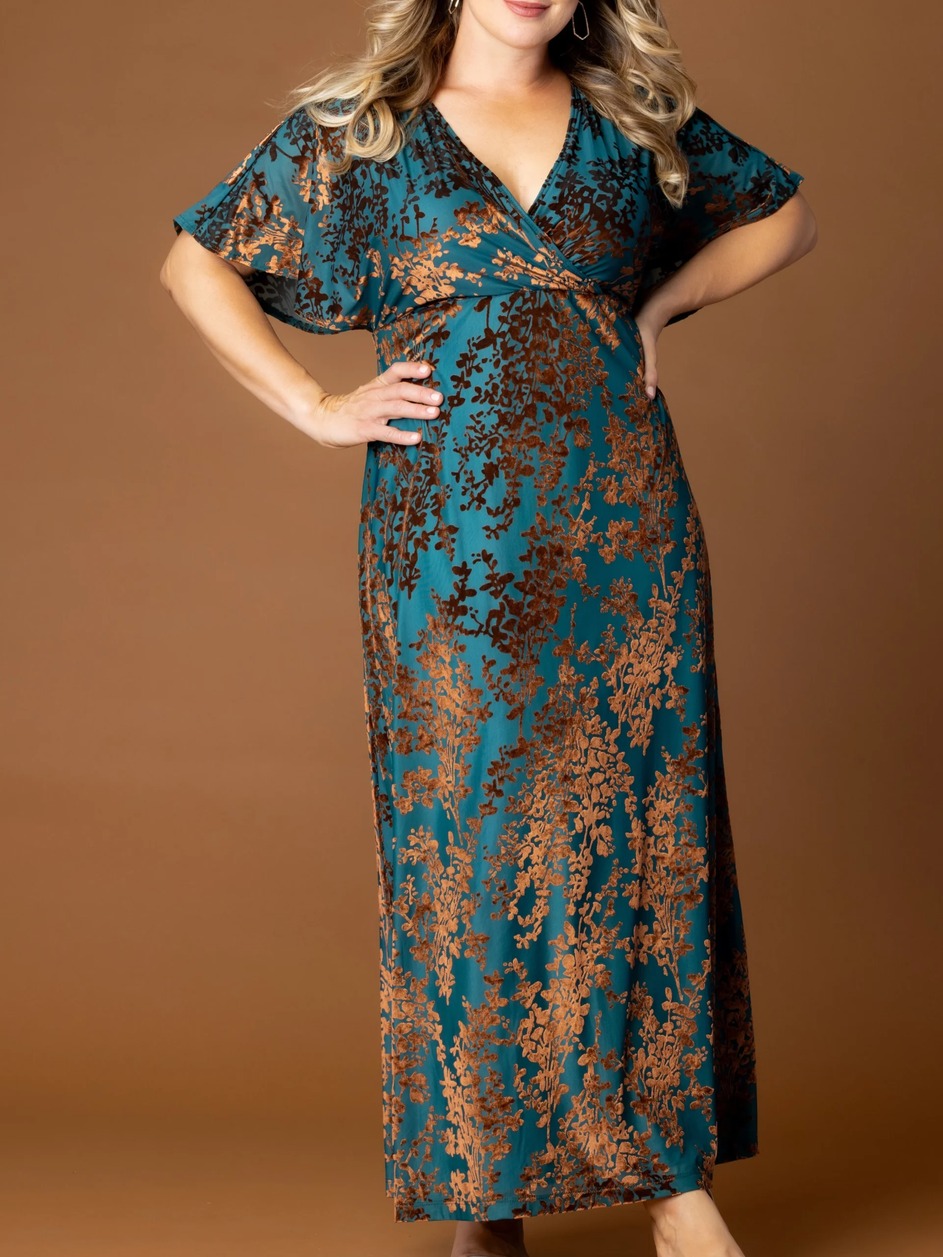 Floor-length teal wrap maxi dress with rust and dark brown floral print and short flutter sleeves.