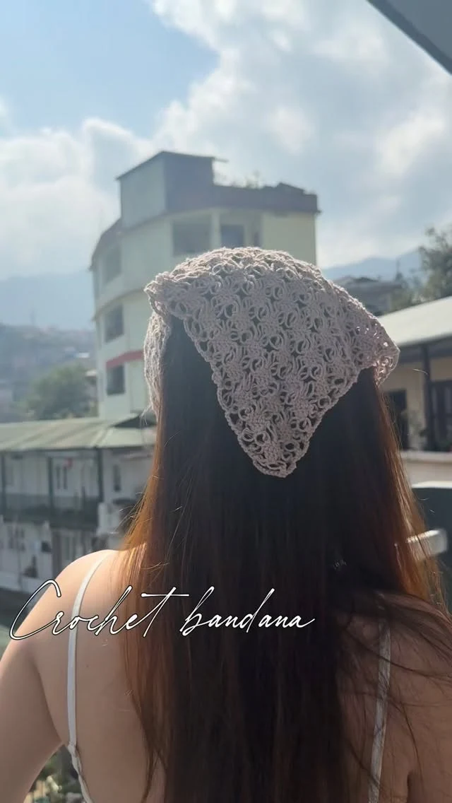 Back view of a white floral crochet bandana over dark hair with a low-back spaghetti strap top.