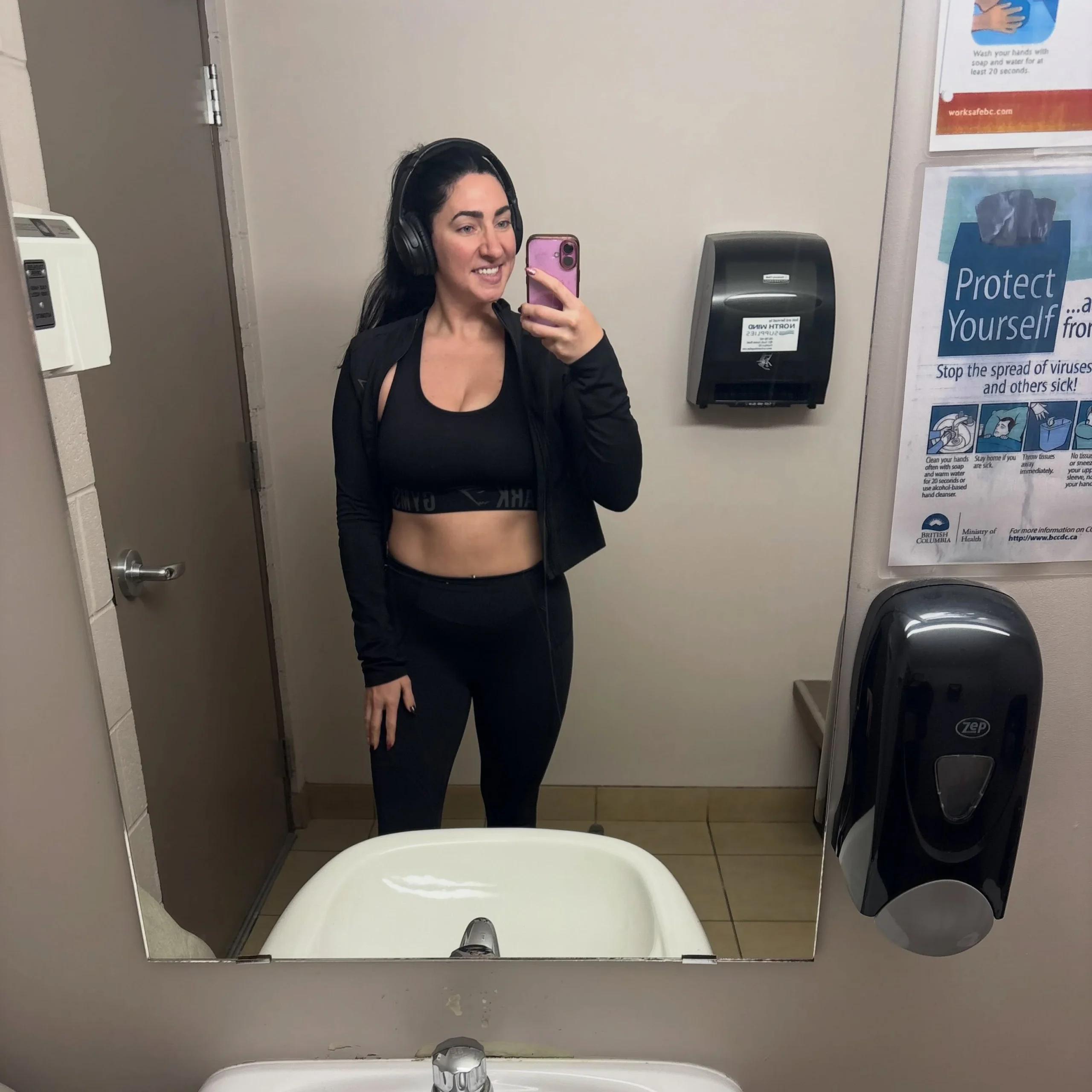 Black sports bra, fitted leggings, and open cropped long-sleeve jacket showing a midriff strip.
