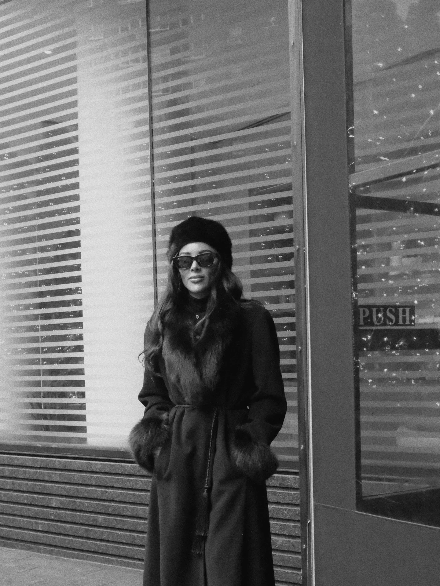 Long dark coat with fur collar and cuffs styled with a matching dark fur hat.