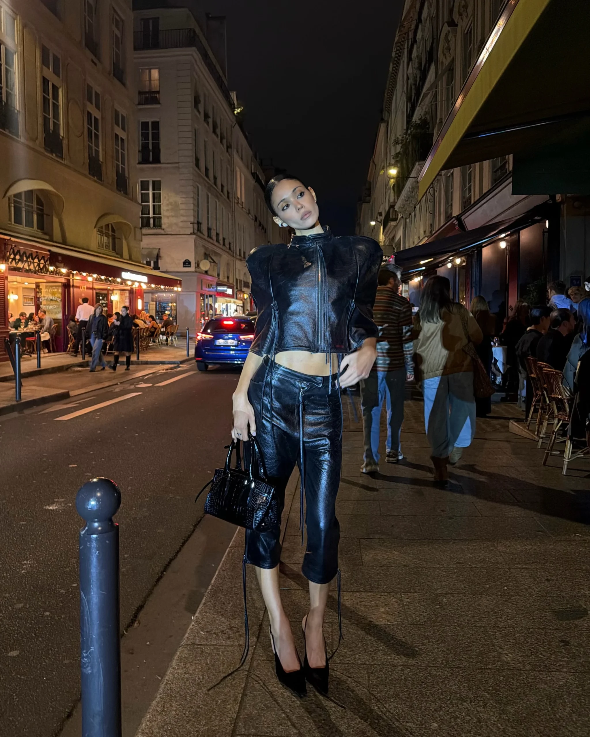 Black cropped high-neck zip leather jacket with oversized shoulders, matching high-waisted leather capri pants, black stiletto heels, small black crocodile-textured handbag