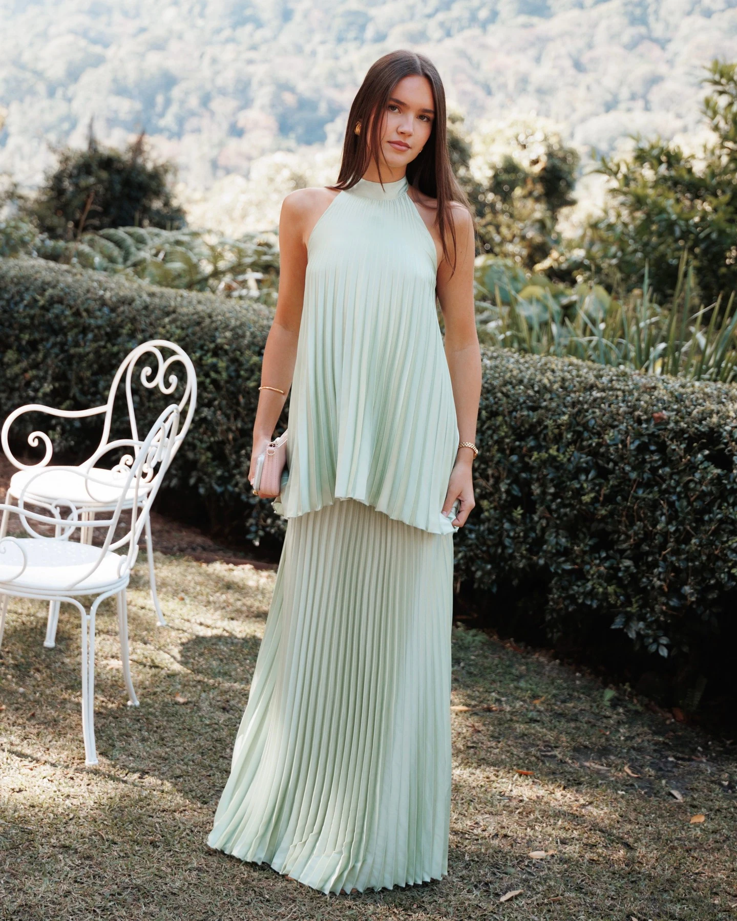 Pale mint pleated halter maxi dress with a loose overlay and small pale pink clutch.