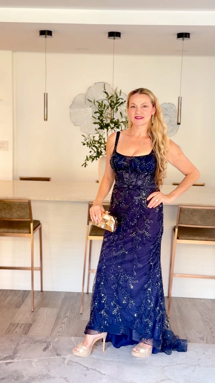 Navy blue sequin mermaid gown with square-neck illusion bodice, satin waist bow, and dramatic train.