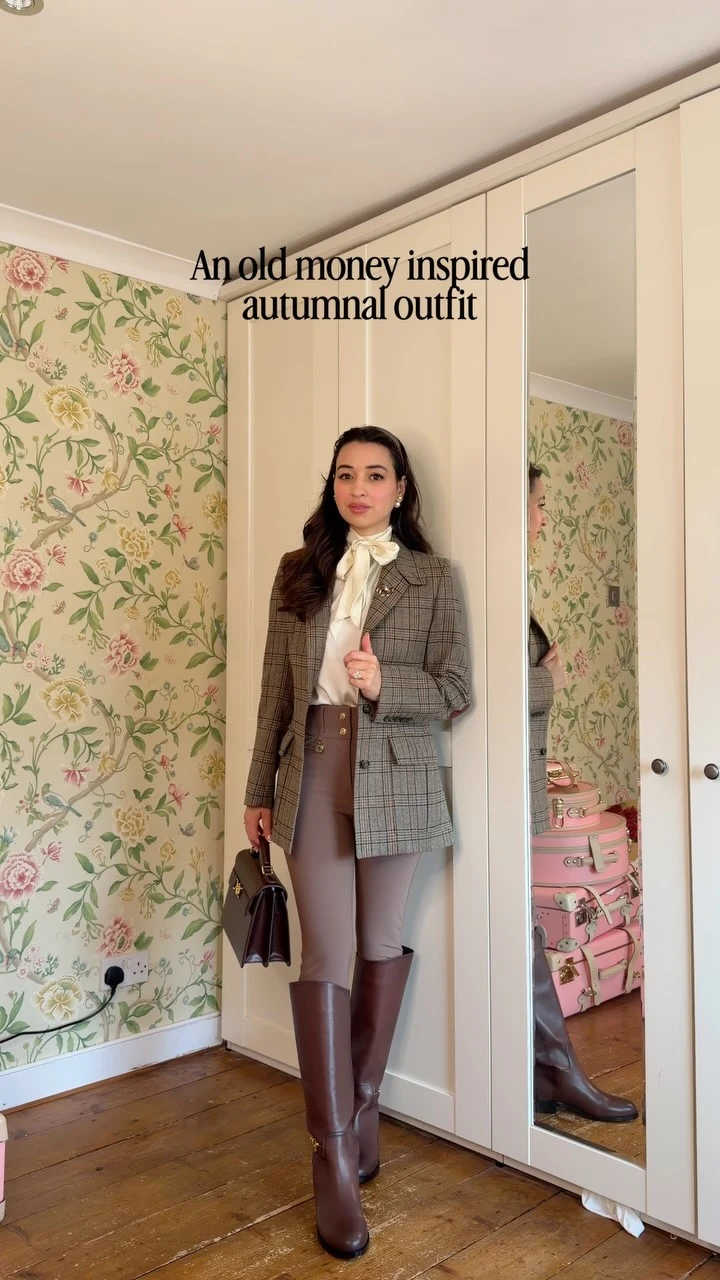 Brown plaid blazer over a white blouse with taupe tights, tall brown boots, and a dark handbag.