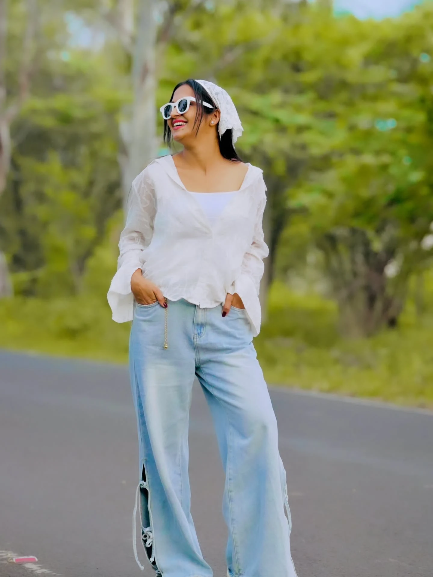 White square-neck blouse and wide-leg jeans with side ties, styled with a white lace head covering and sunglasses.