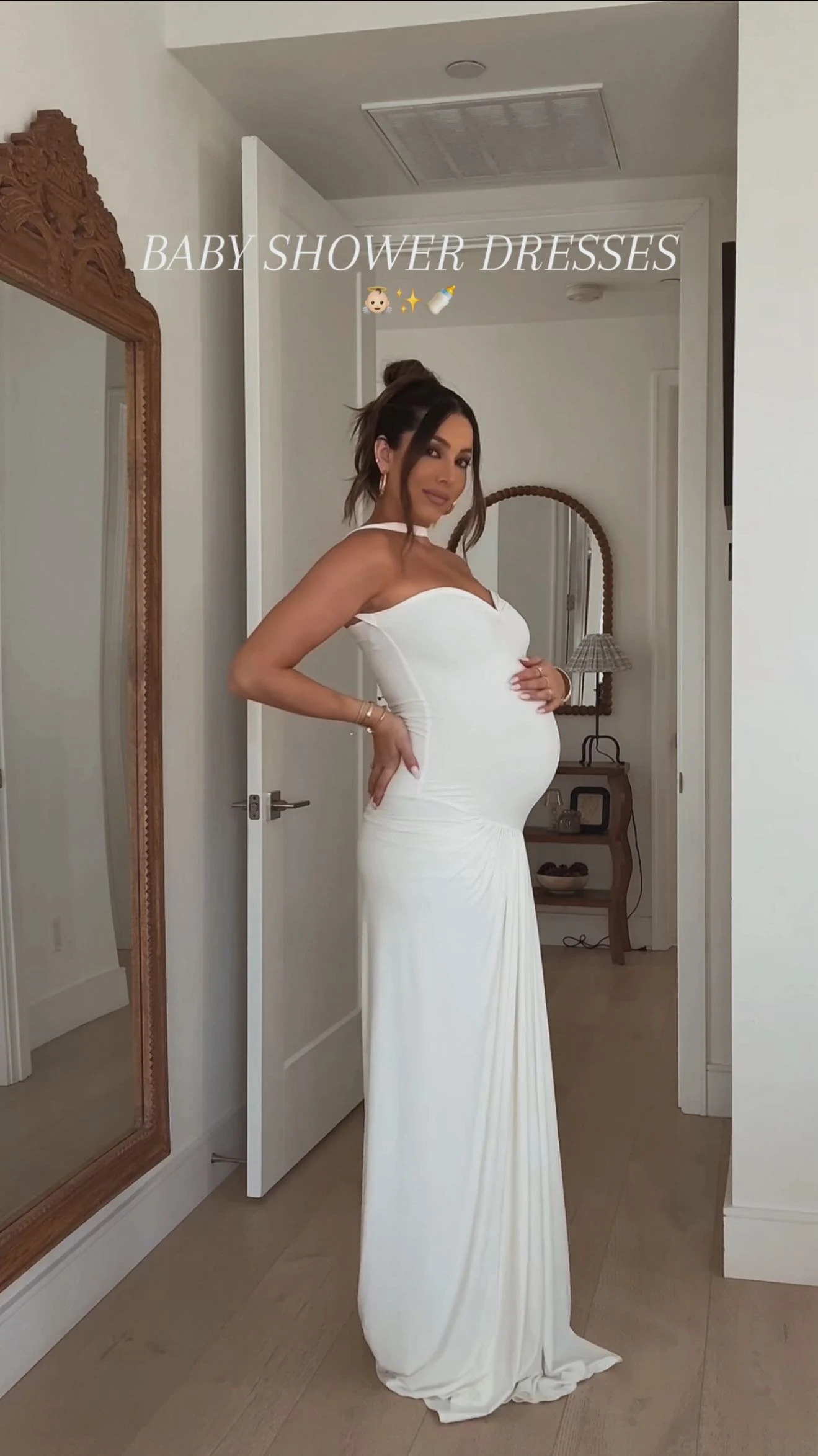 Pregnant woman in a white strapless sweetheart gown with a floor-length straight skirt and hair in a bun.