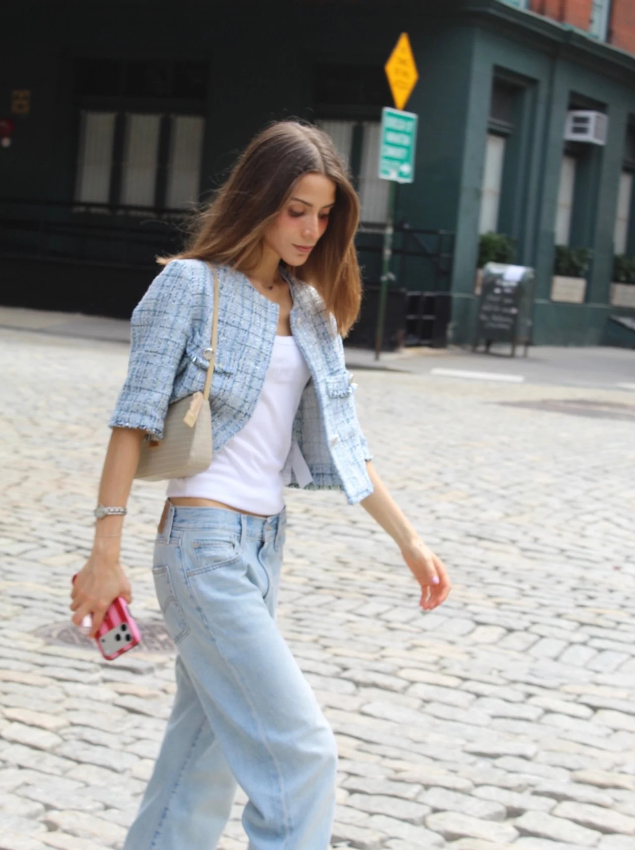 Light blue textured cropped jacket over a white top, loose light-wash jeans, and a beige shoulder bag.