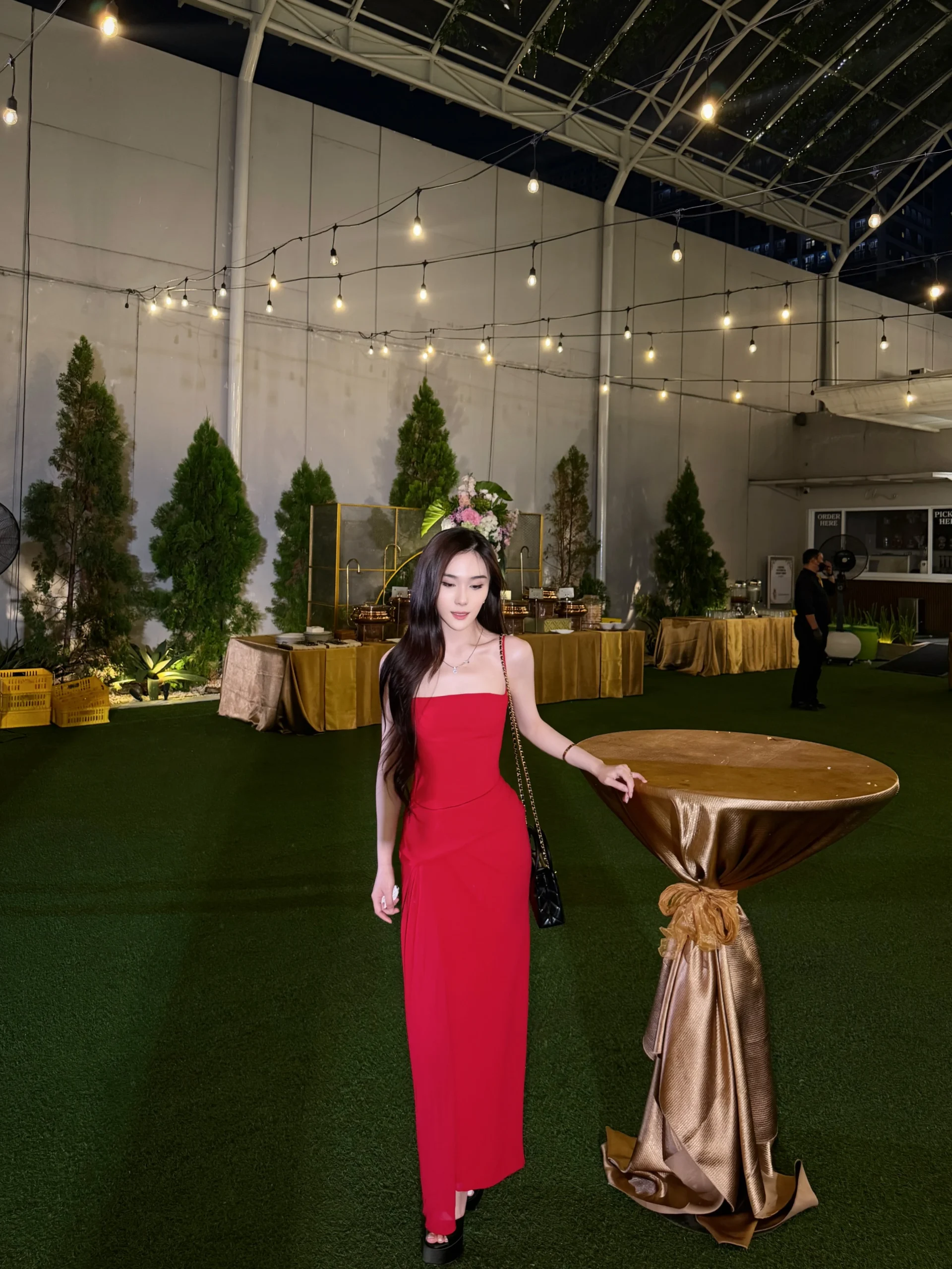 Woman wearing a bright red strapless form-fitting maxi dress with black platform heels.