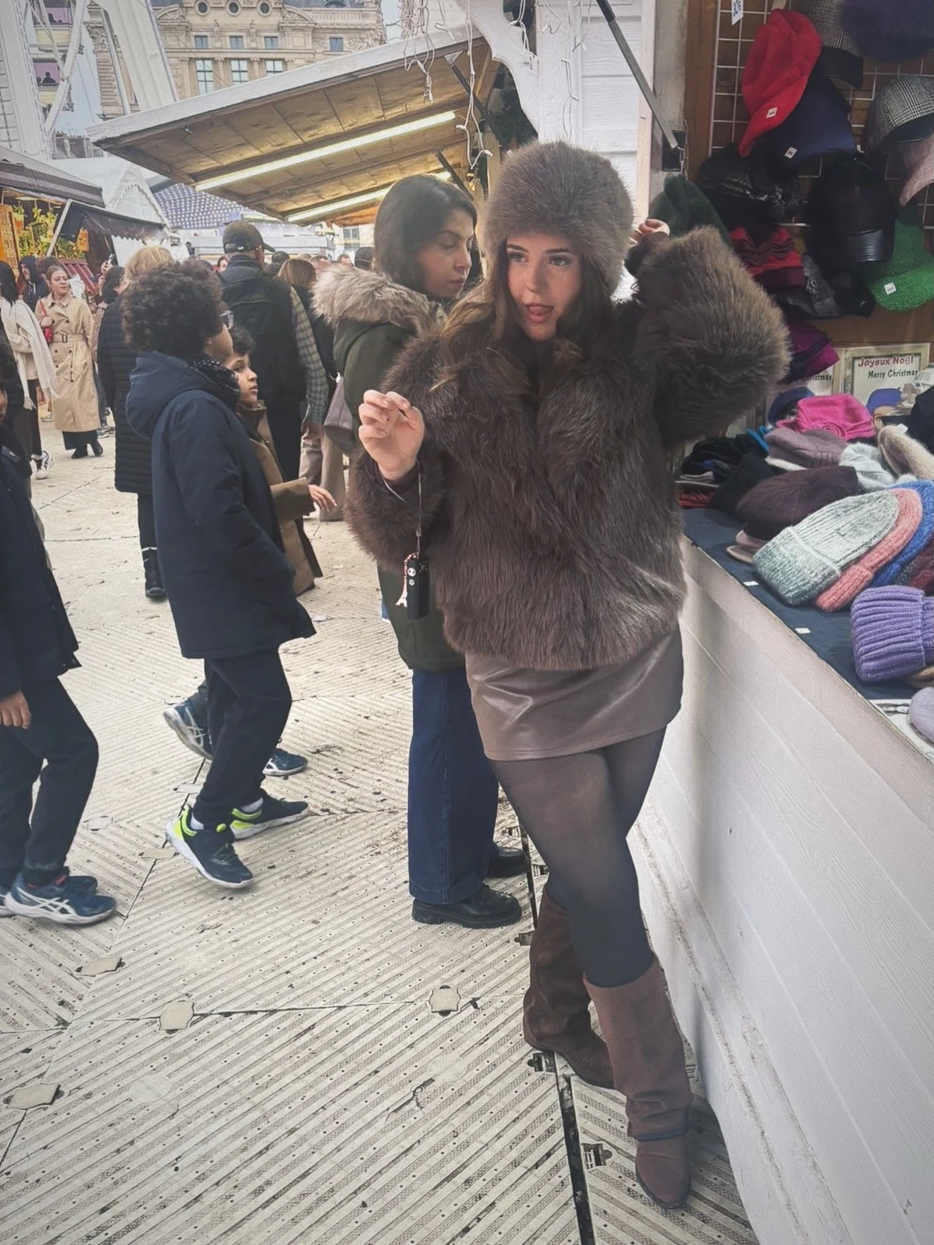 Brown faux-fur cropped jacket, fur hat, taupe leather mini skirt, black tights, brown knee-high boots