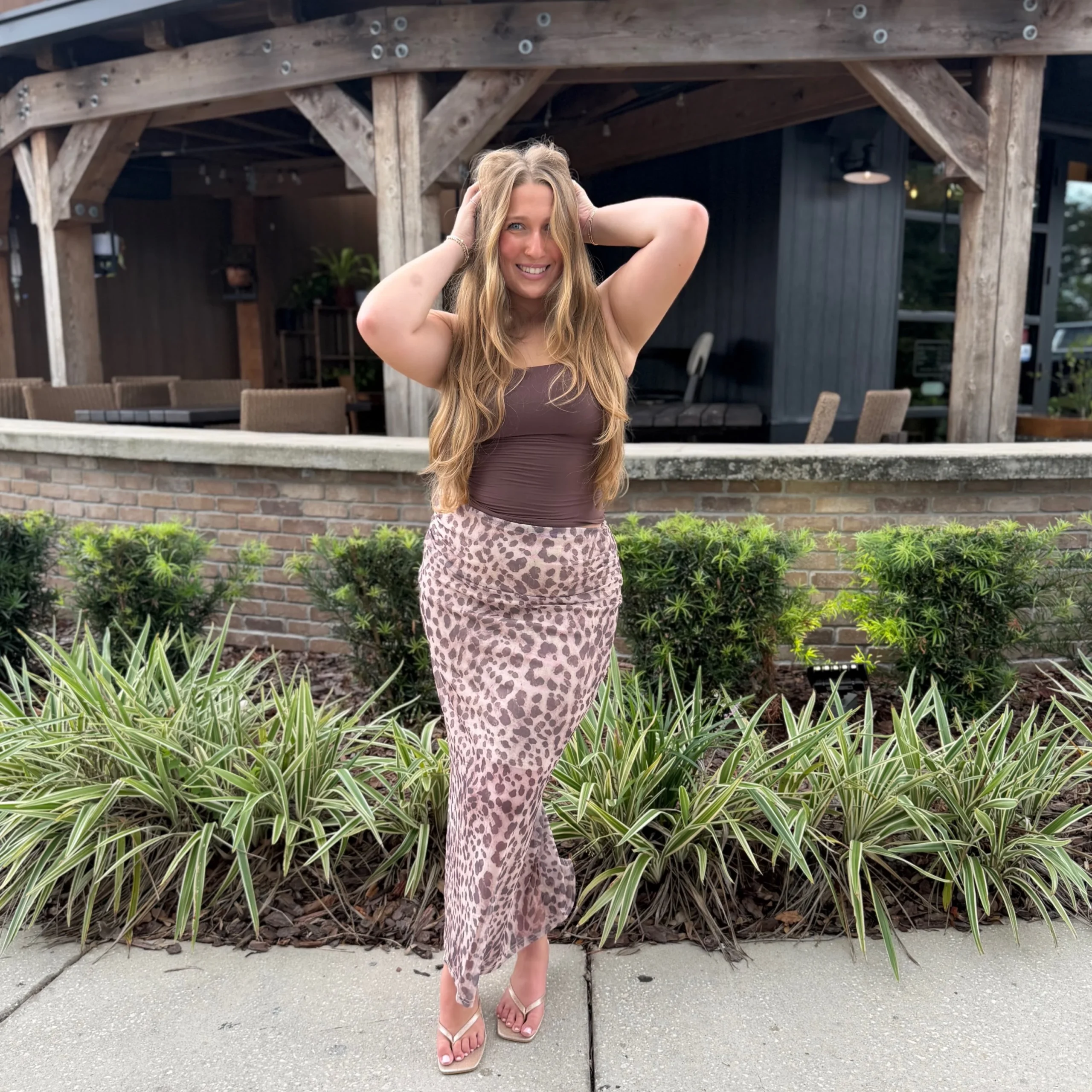 Brown strapless tube top with a pink leopard-print midi skirt and metallic heeled sandals.