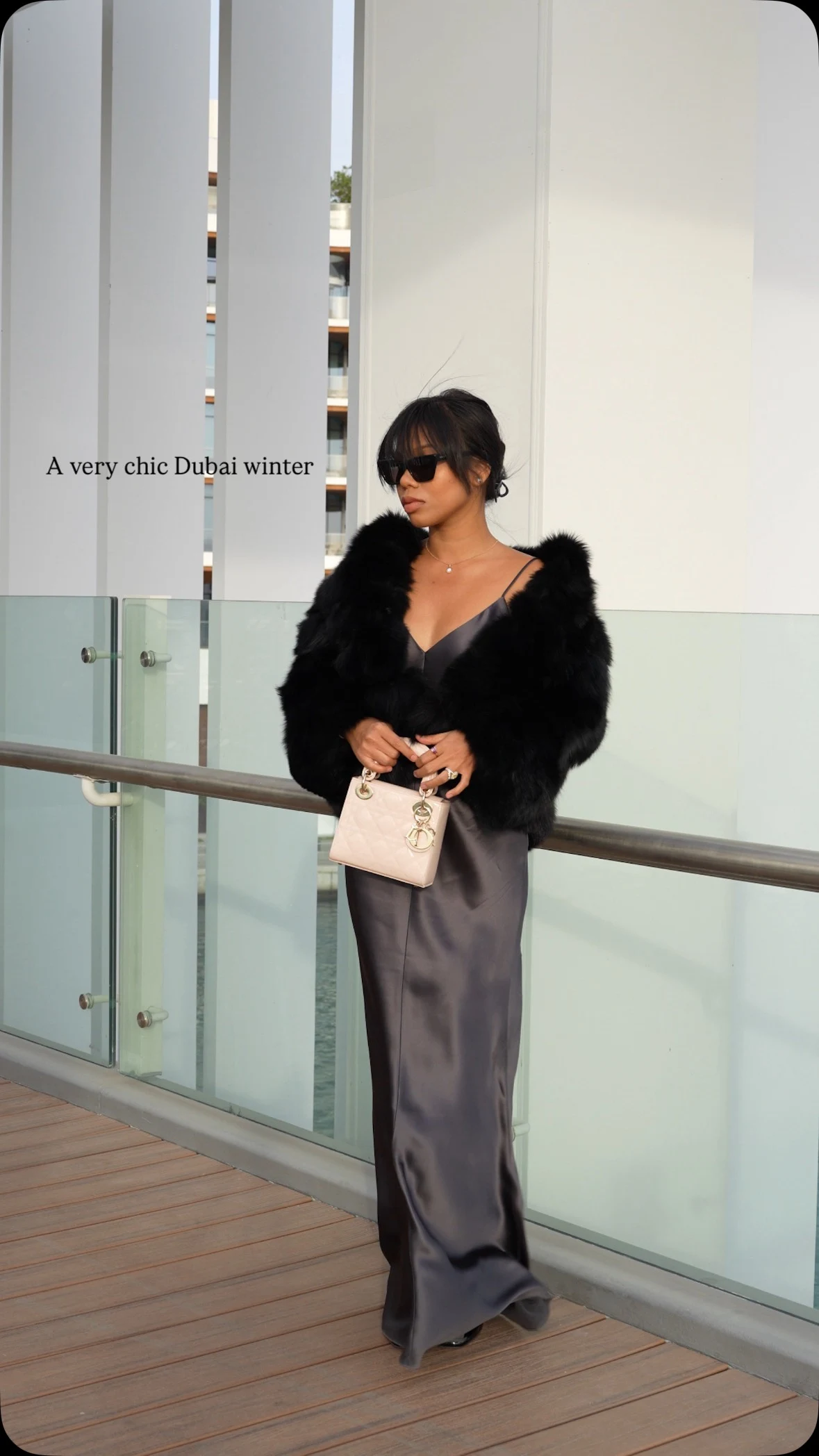 Dark gray floor-length slip dress under an open black fur jacket, with a pale pink handbag.