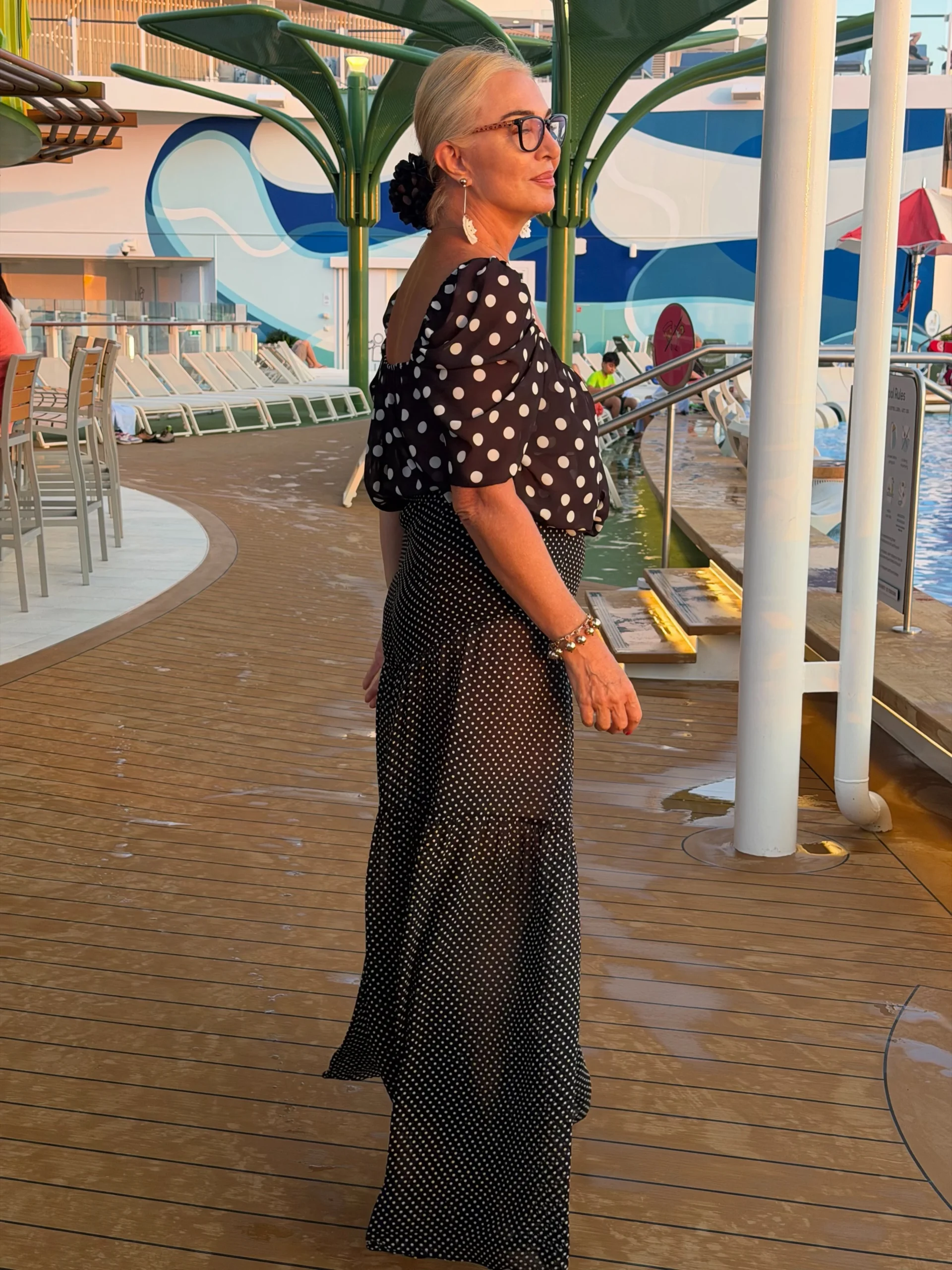 Woman in a large polka dot black blouse and a flowing black-and-white small dot maxi skirt.