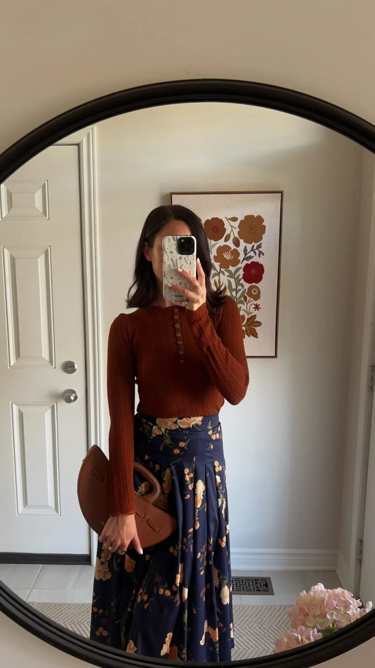 Fitted rust-brown ribbed top paired with a high-waisted navy pleated maxi skirt with large muted florals.