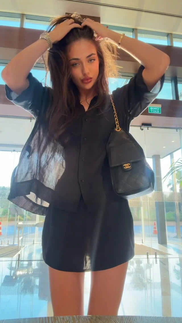 Sheer black button-up shirt open over black mini dress, black tights, black ankle boots