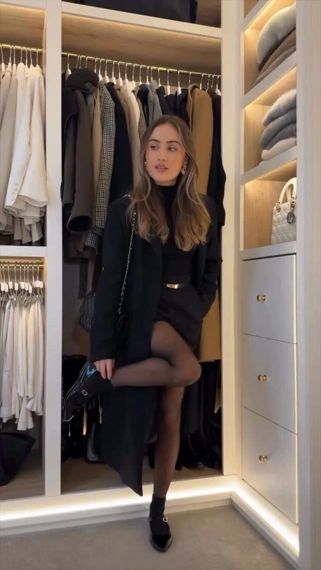 Woman wearing a beige wool coat, cream knit sweater, wide-leg pants, and brown ankle boots.