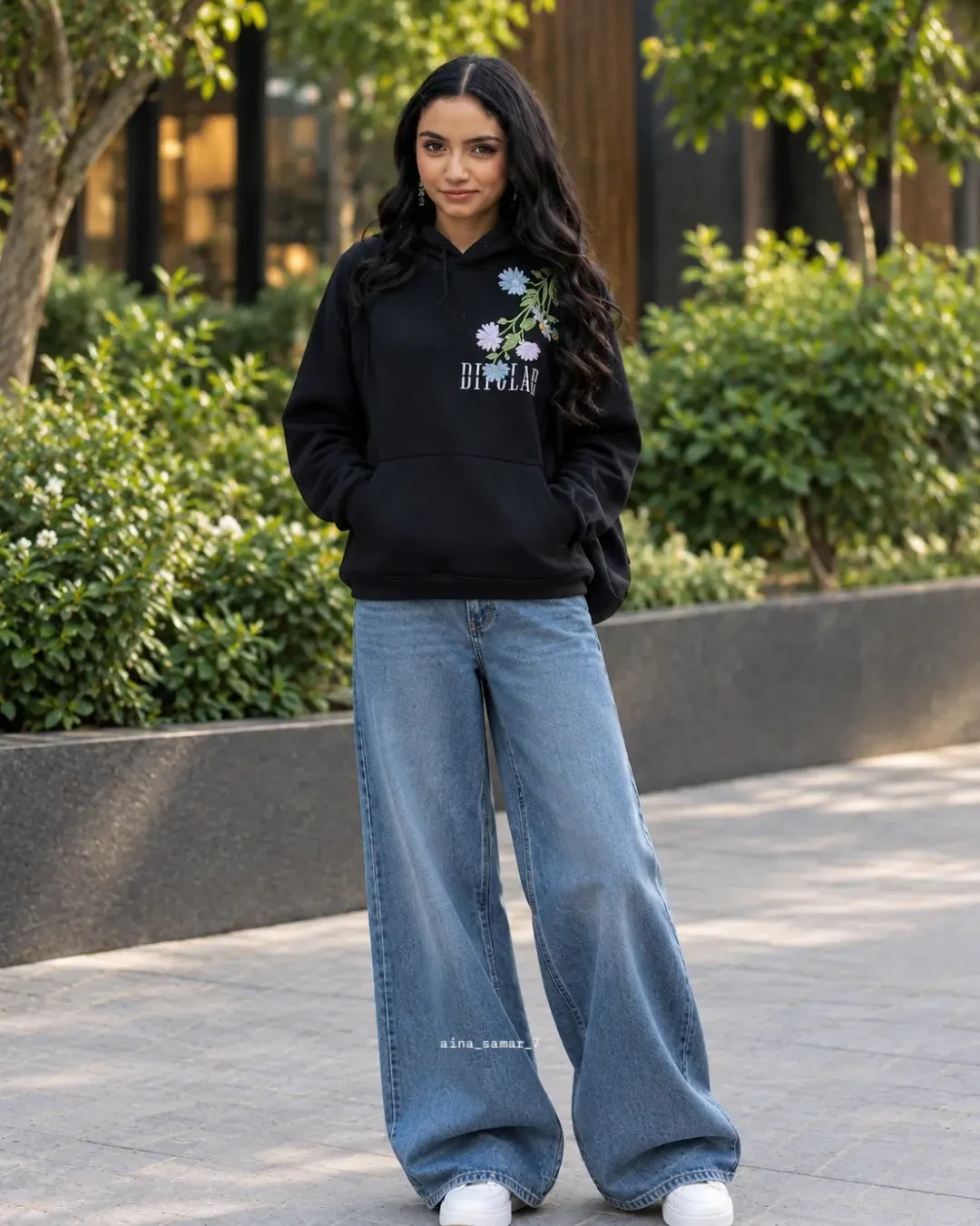Black floral hoodie and light blue wide-leg jeans worn with white sneakers outdoors.
