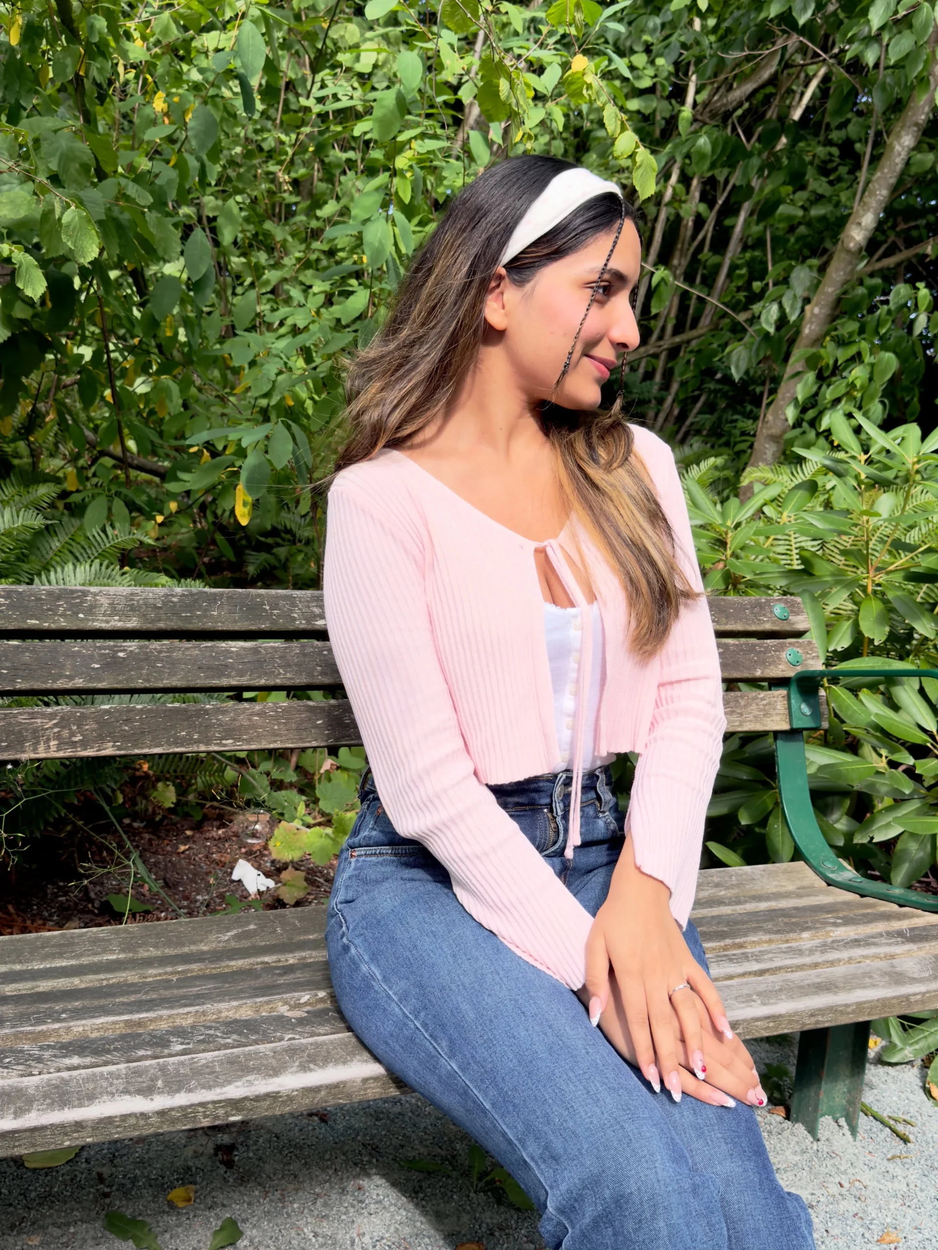 light pink ribbed cropped cardigan with tie-front over white button top, high-waisted blue jeans, white headband