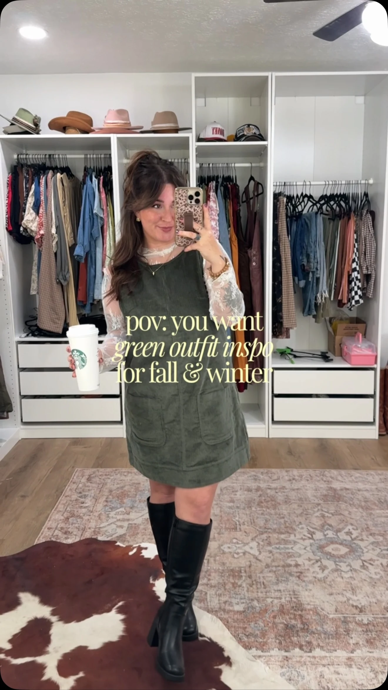 Olive green pinafore mini dress over a white lace top with black knee-high boots.