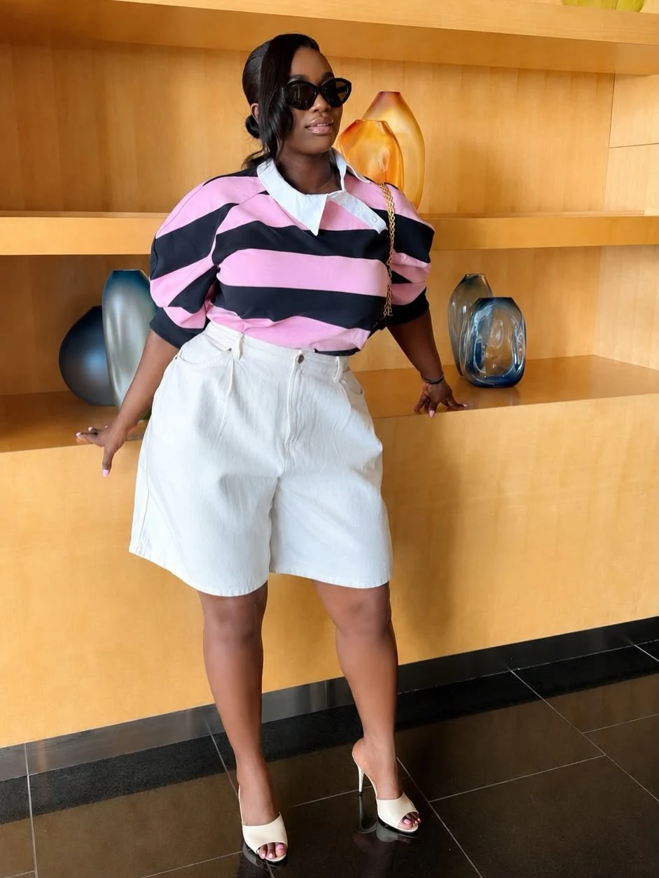 Pink and black striped rugby polo tucked into white high-waisted shorts with cream stiletto mules.