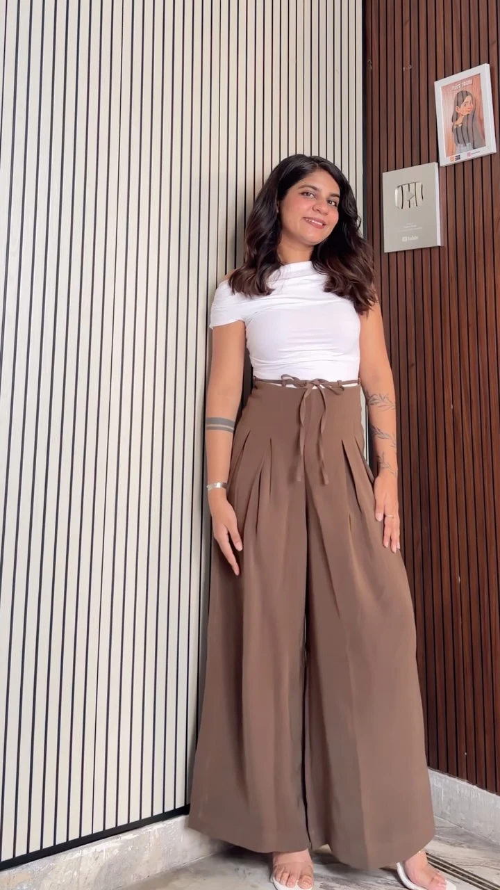 Fitted white high-neck top paired with high-waisted wide-leg brown trousers with a tied waist.