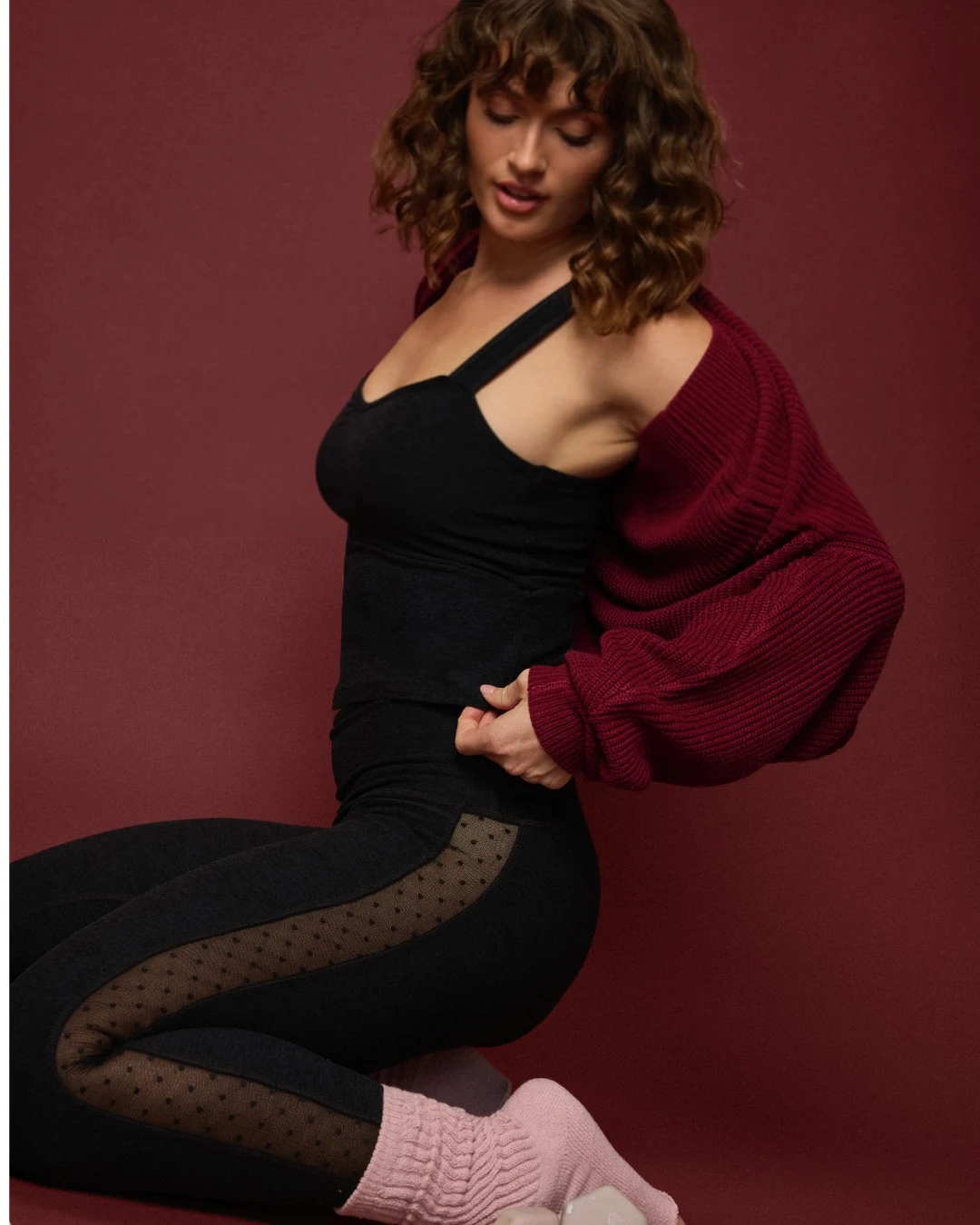 Black sleeveless top and leggings styled with a burgundy cardigan and pink leg warmers.