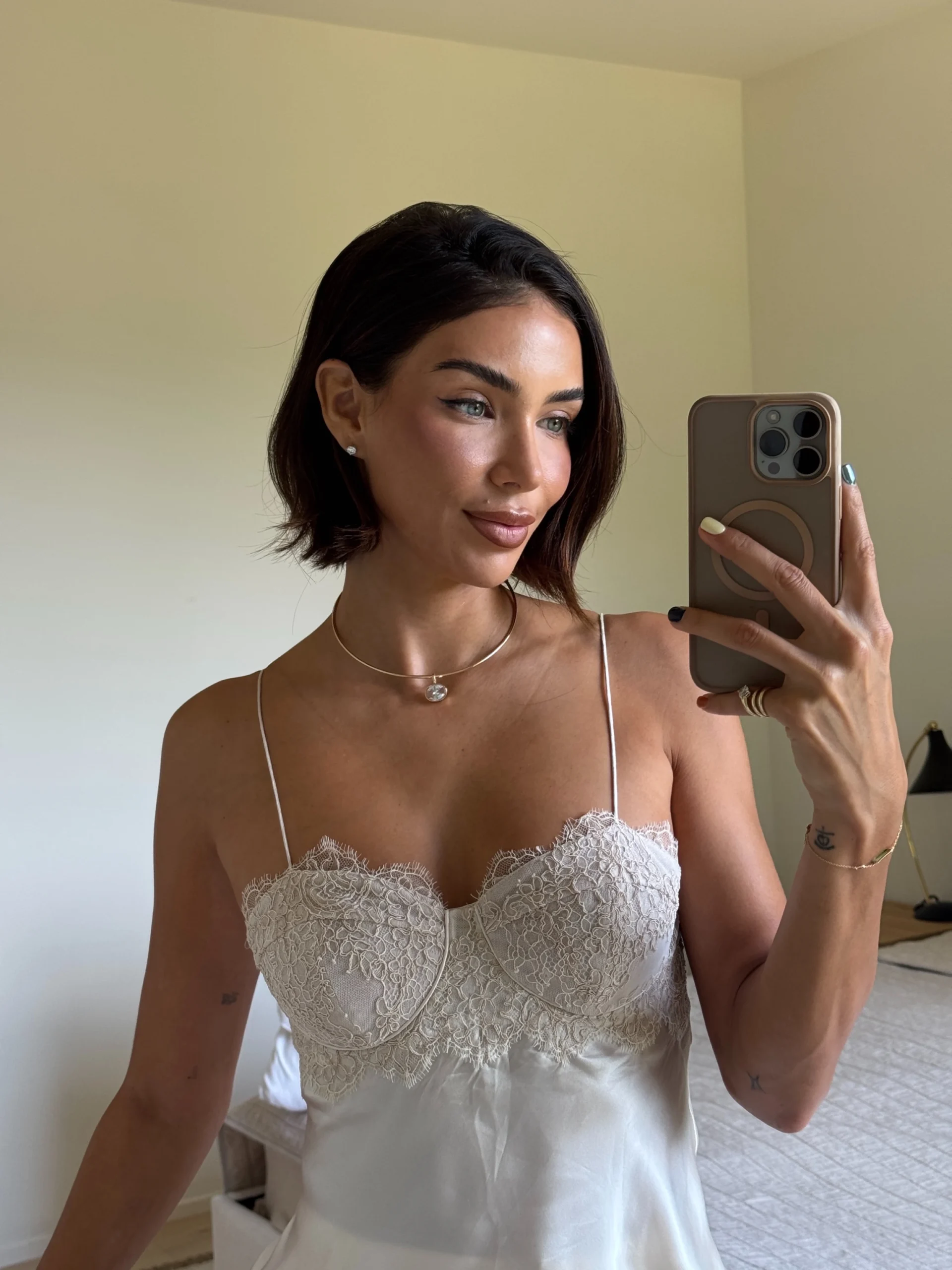 Cream satin lace bustier camisole with thin straps paired with loose white linen pants.