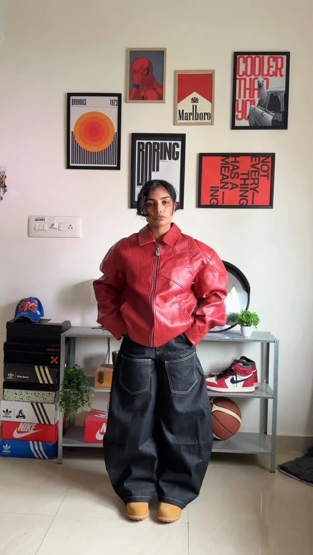 Cropped puffy red leather jacket with a circular back emblem styled over wide-leg dark jeans and tan boots.