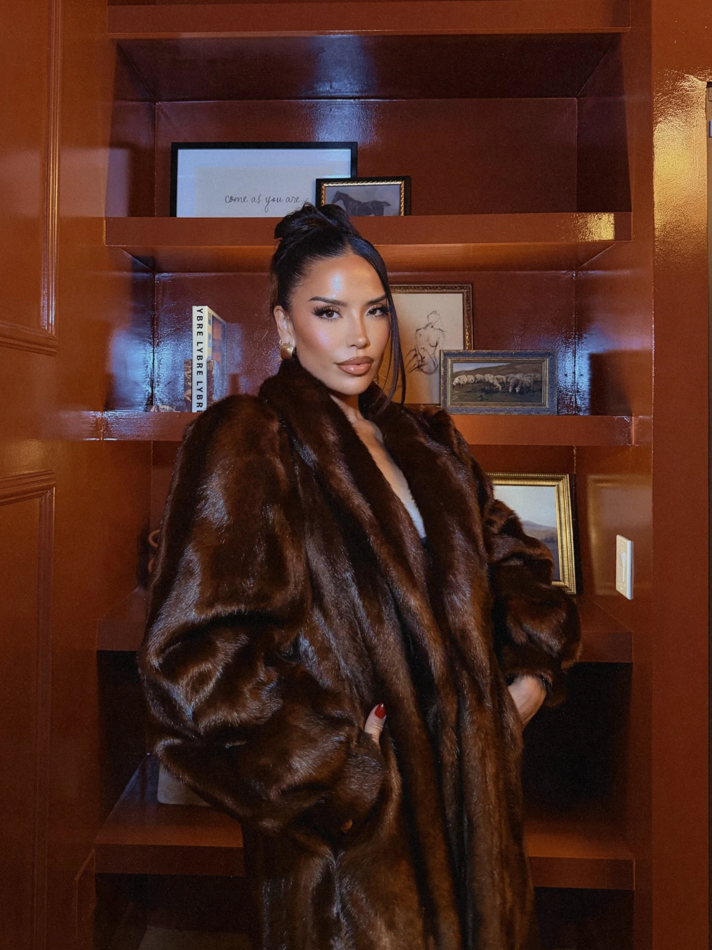 Person wearing an oversized open dark brown fur coat with a broad collar and voluminous sleeves.